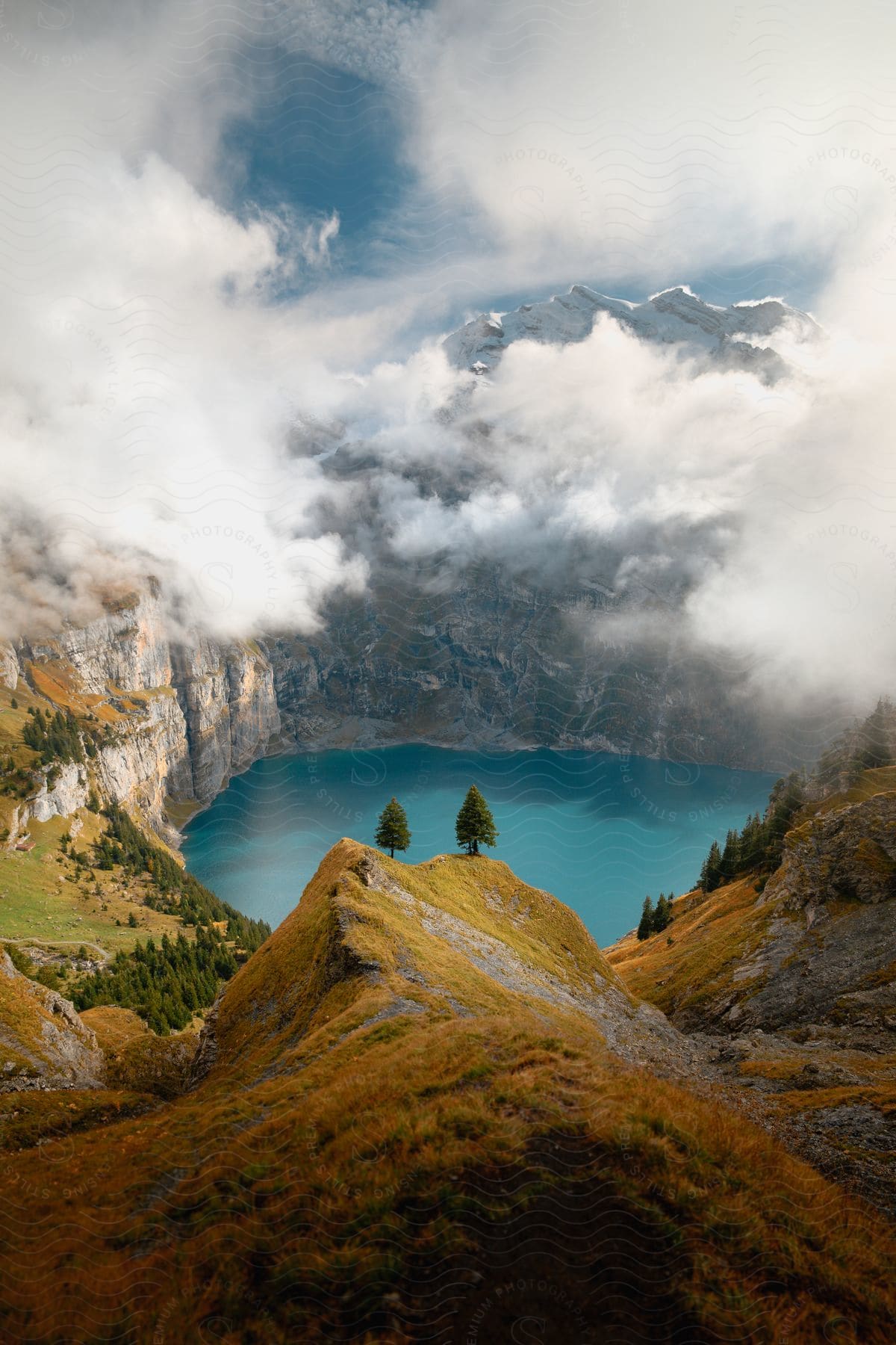 A blue lake sits in a deep canyon surrounded by steep mountains on a partly cloudy day.