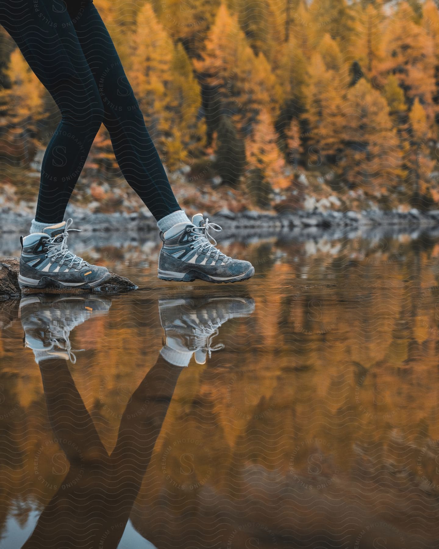 a woman on tight walking on top of water in the woods with her boots