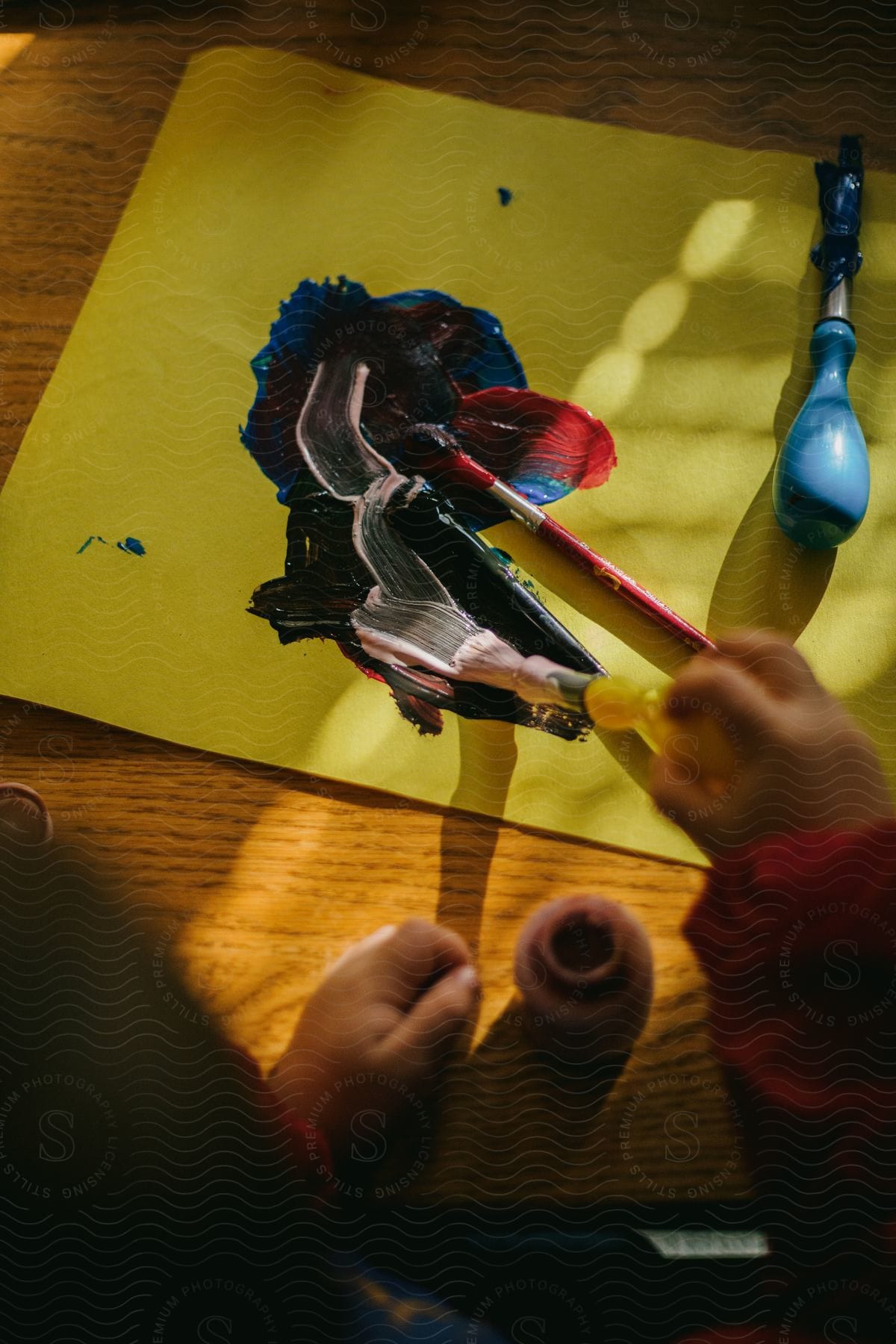 A child is holding a paint brush and painting a picture