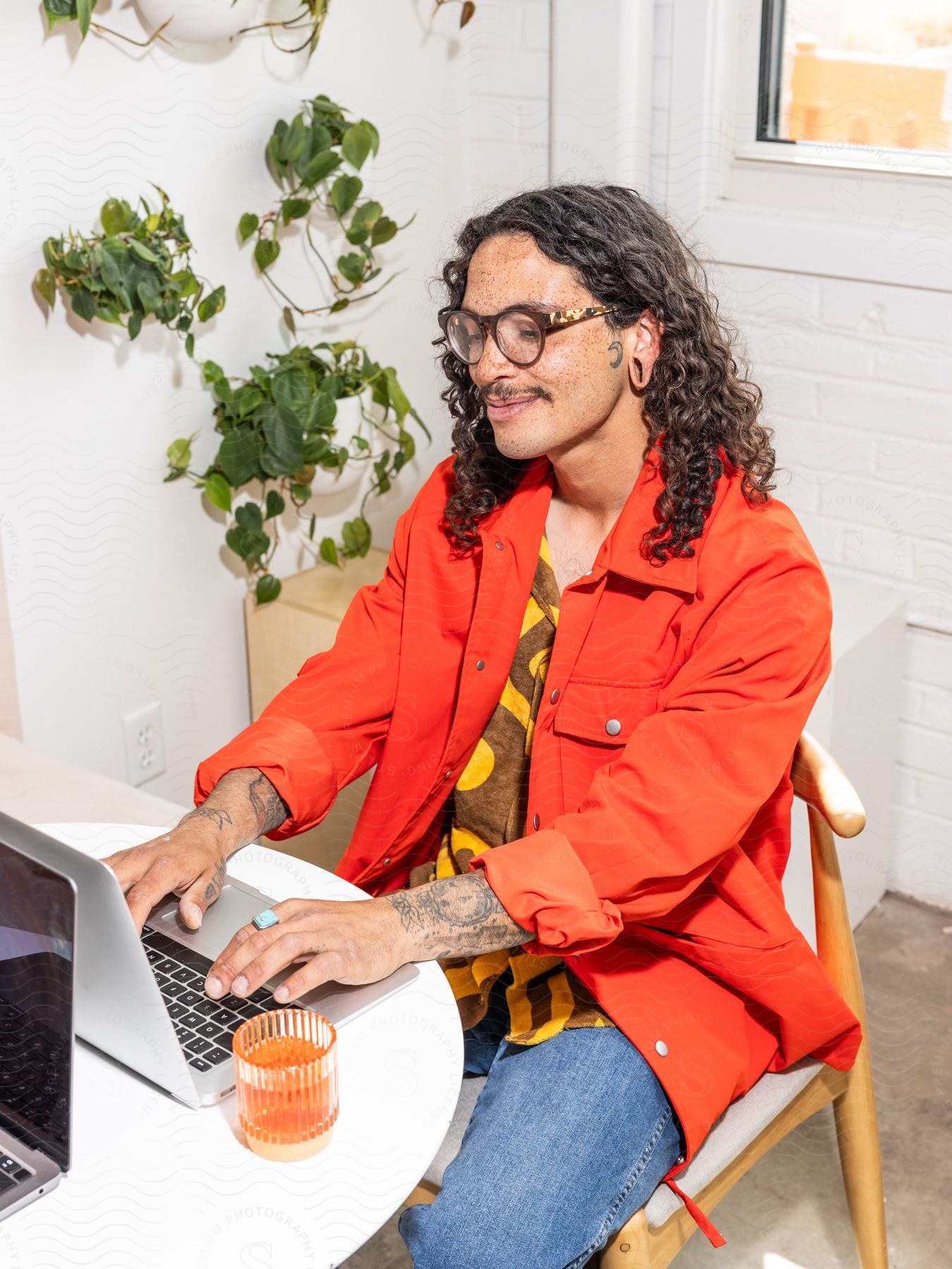 A man smiles as he sits at a table typing on a laptop computer