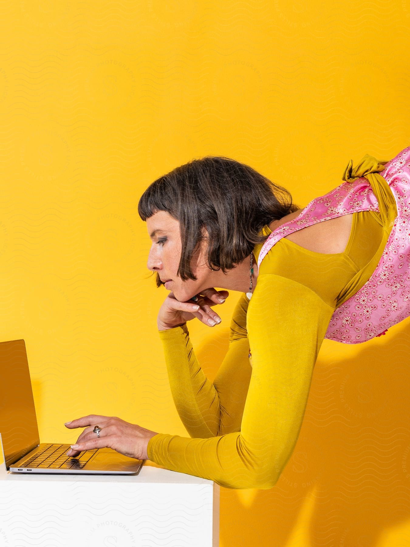 Stock photo of a woman is leaning down and typing on a laptop computer on a white table