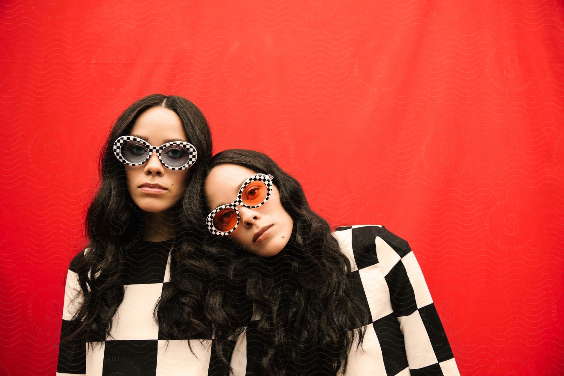 Two women are wearing matching shirts and sunglasses.