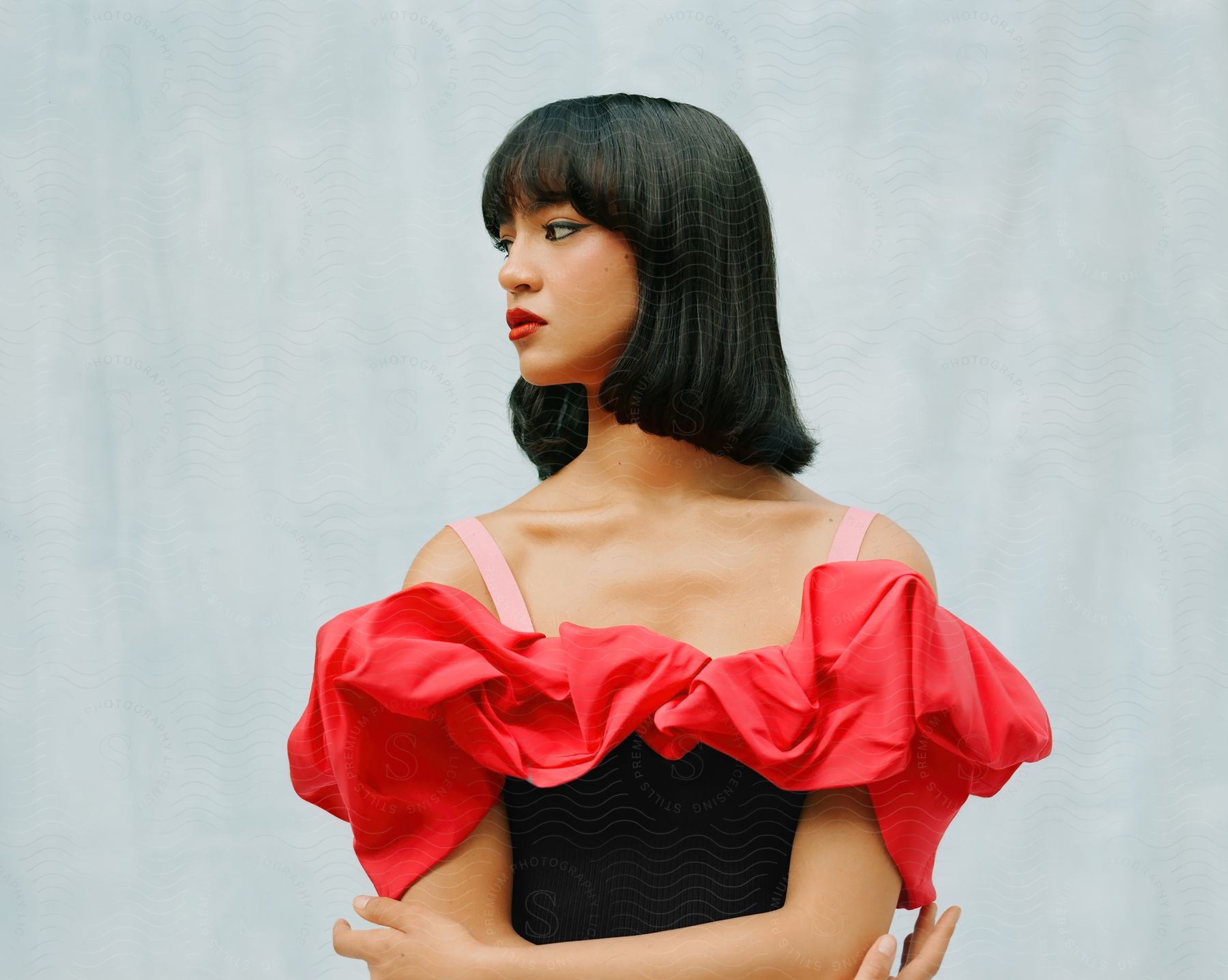 An Asian woman in a black dress with red ruff and pink shoulder straps.