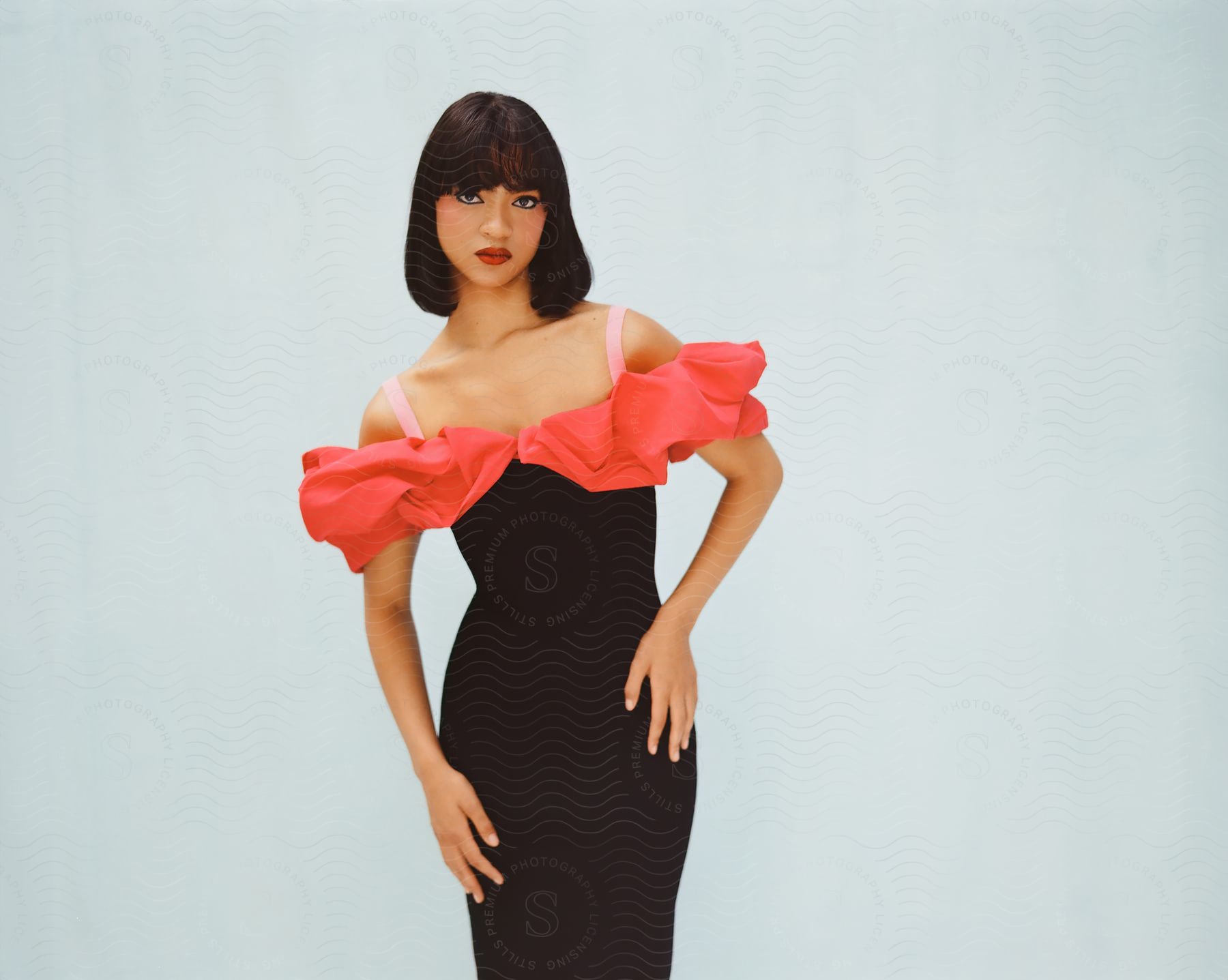 Woman modeling in a black and pink dress against a white background.