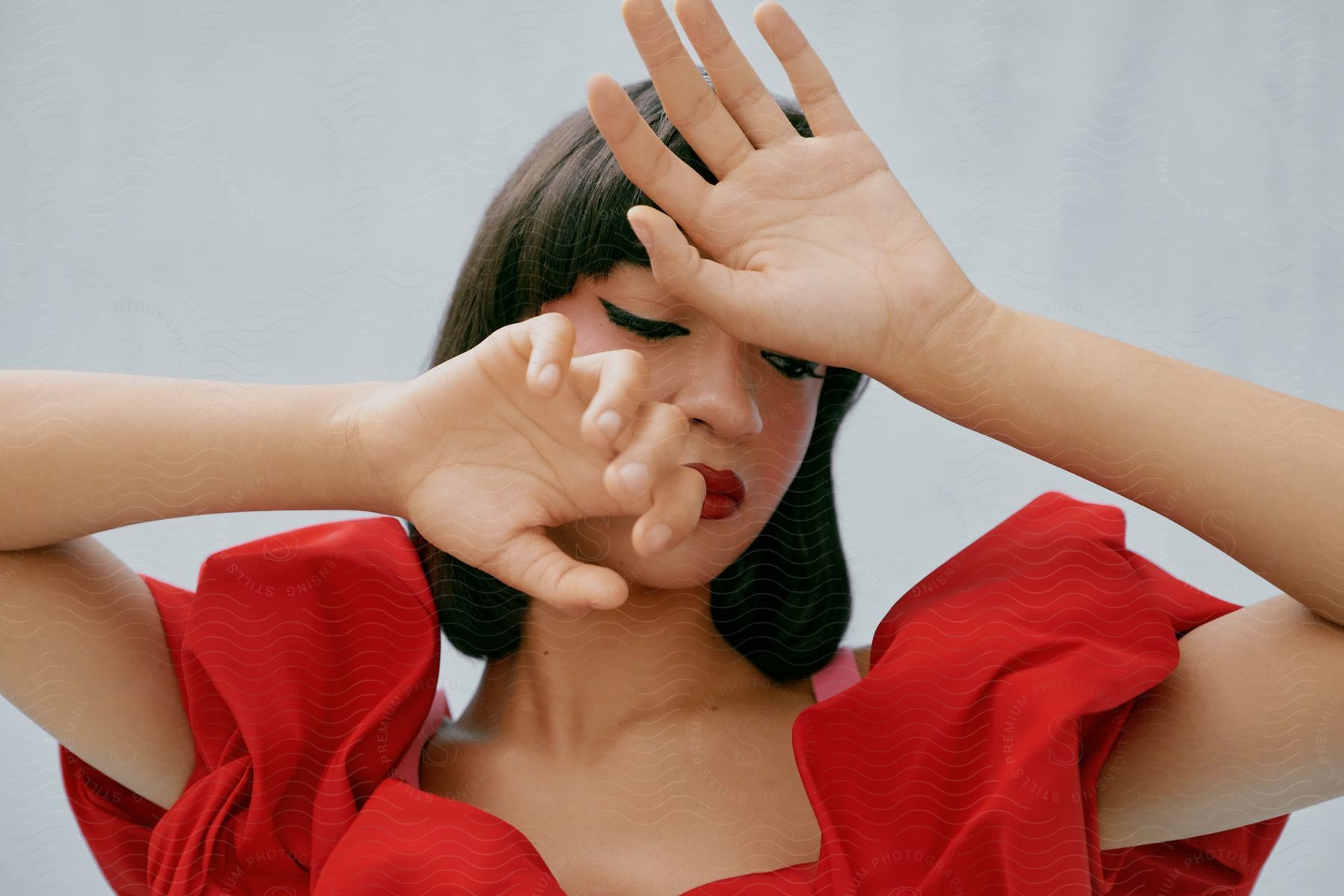 An Asian woman in a red ruff holds her hands like claws in front of her face.