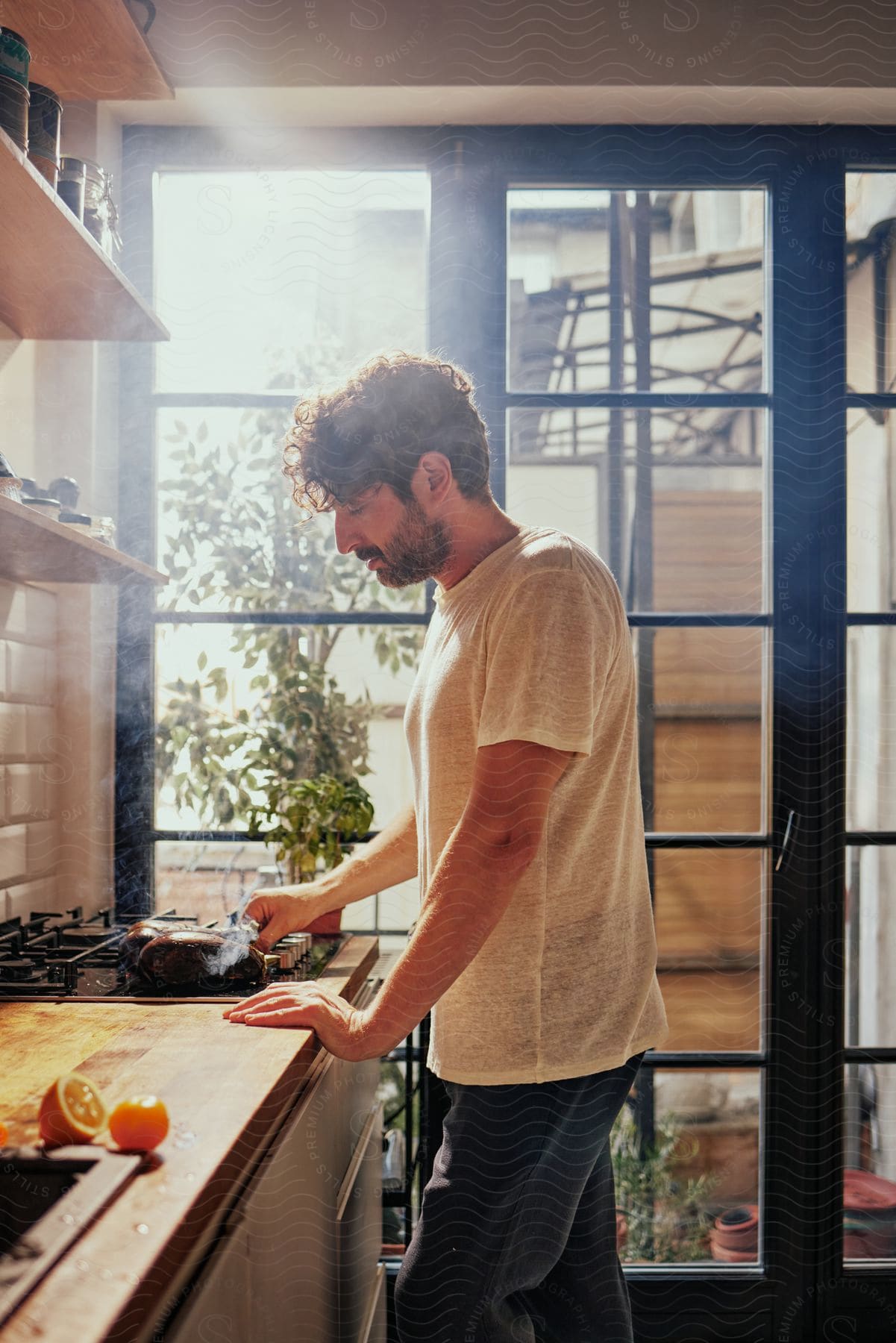 A man is cooking something on the stove on a sunny day.