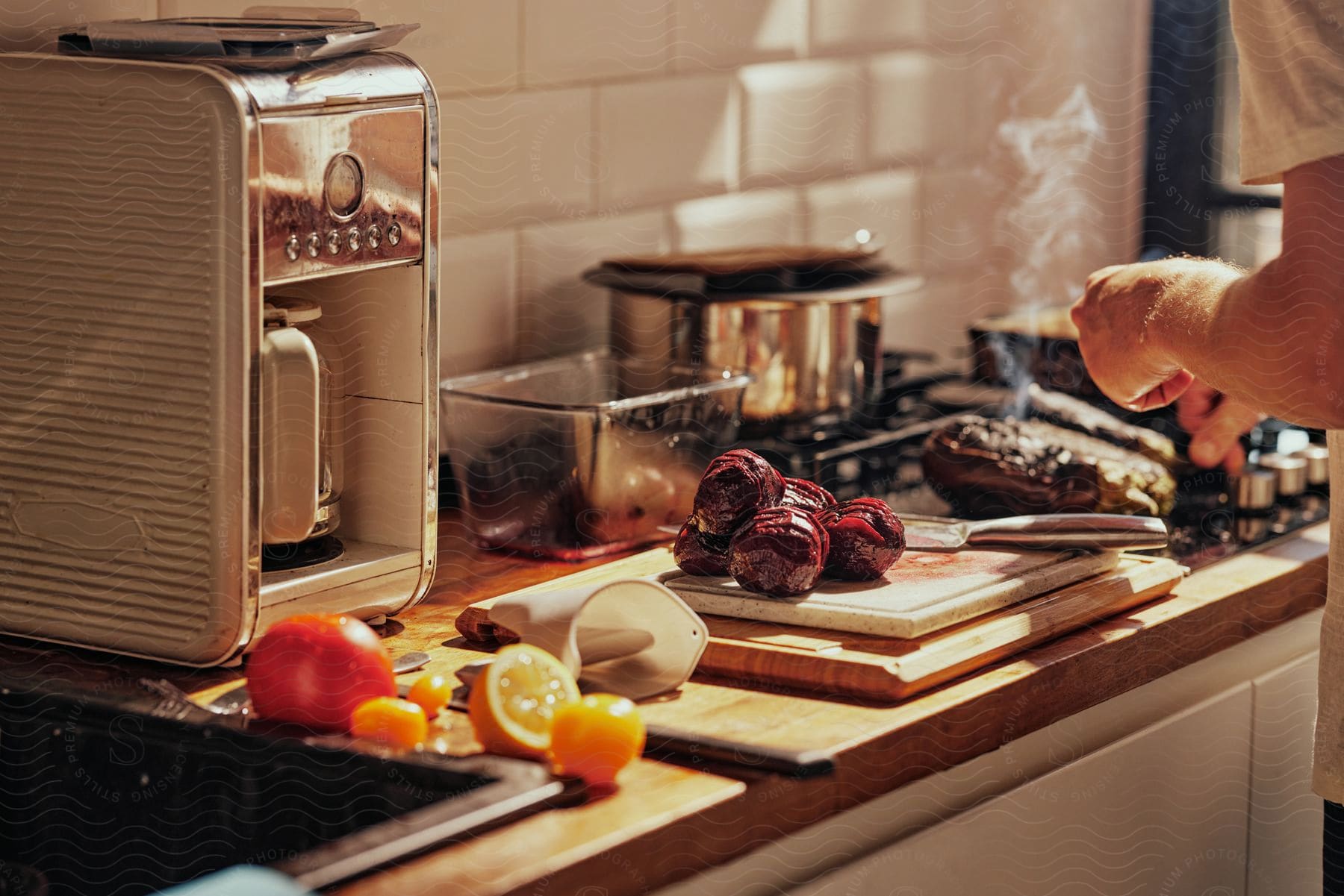 person standing at stove prepares beets and oranges