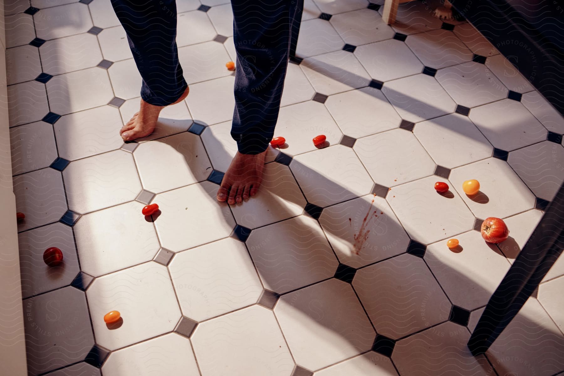 A man stands barefoot with fruits scattered on the floor