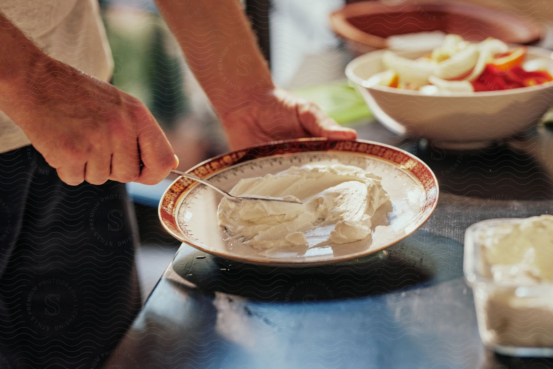 Close-up of a man's hands holding cutlery over a plate with white cream.