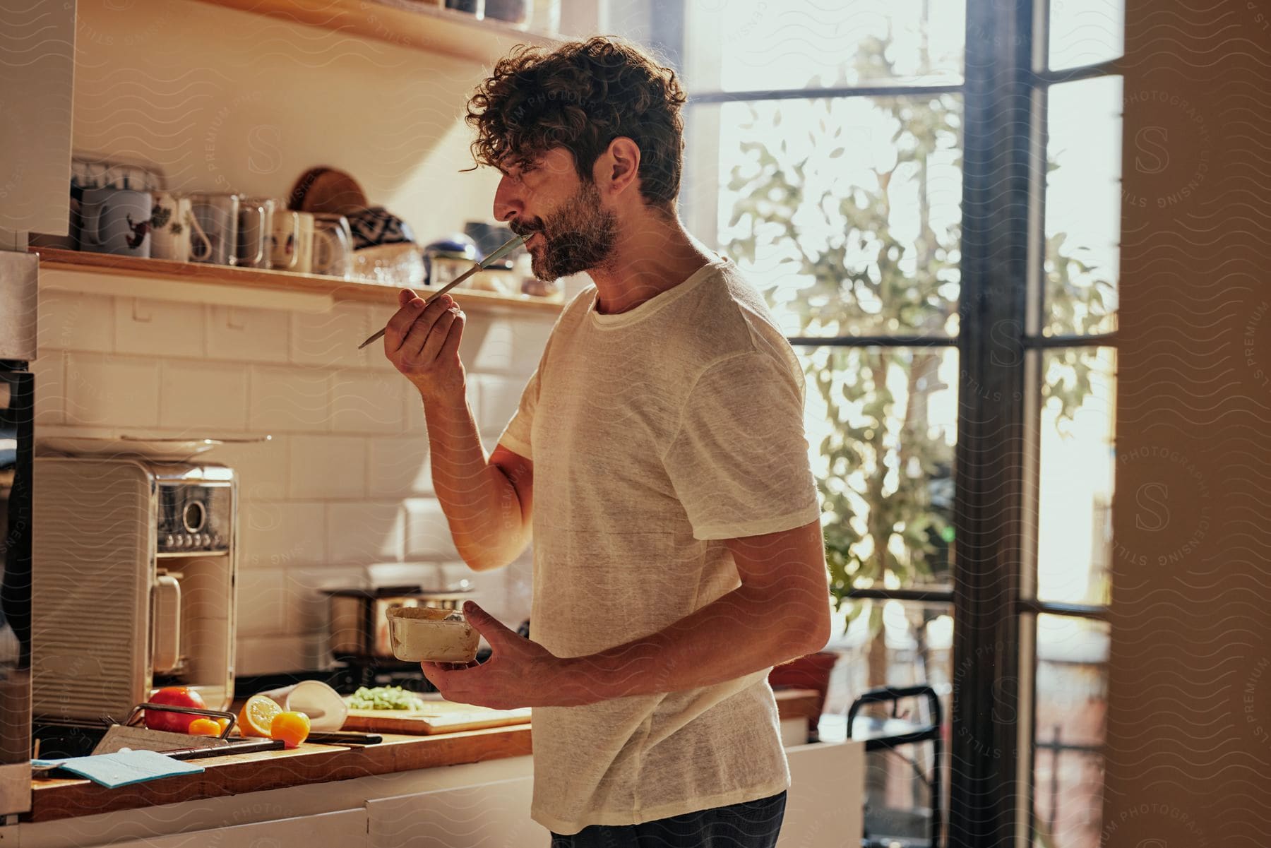 Man cooking and tasting food with a spatula.