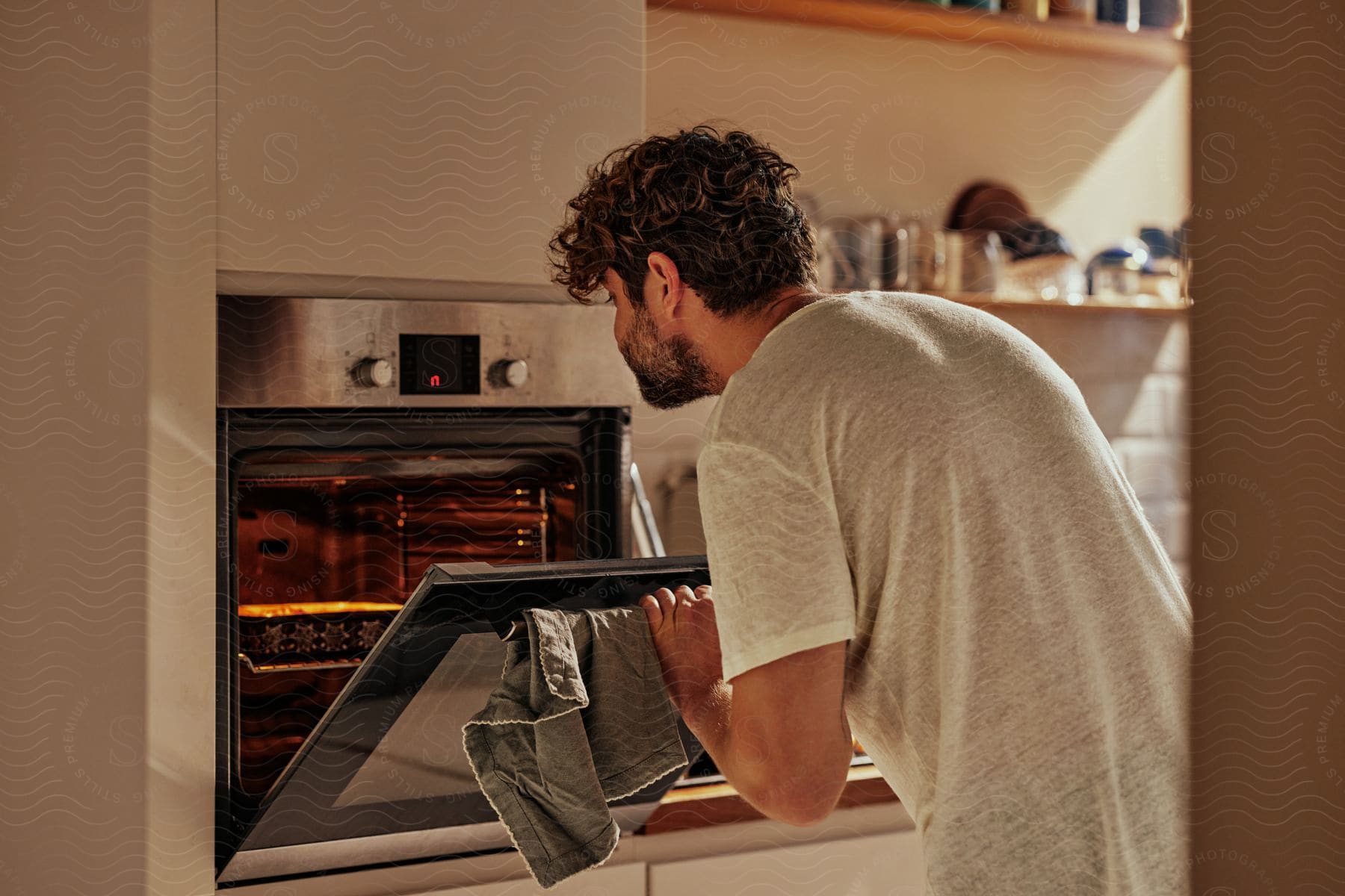 A man is checking on the meal he has cooking in the oven.