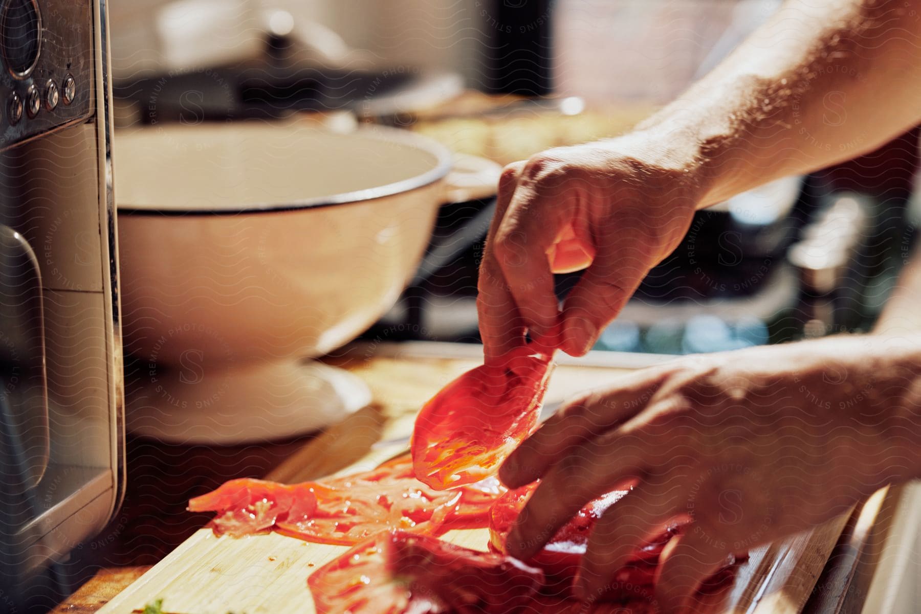 A person is stacking thin cut tomatoes on top of each other.