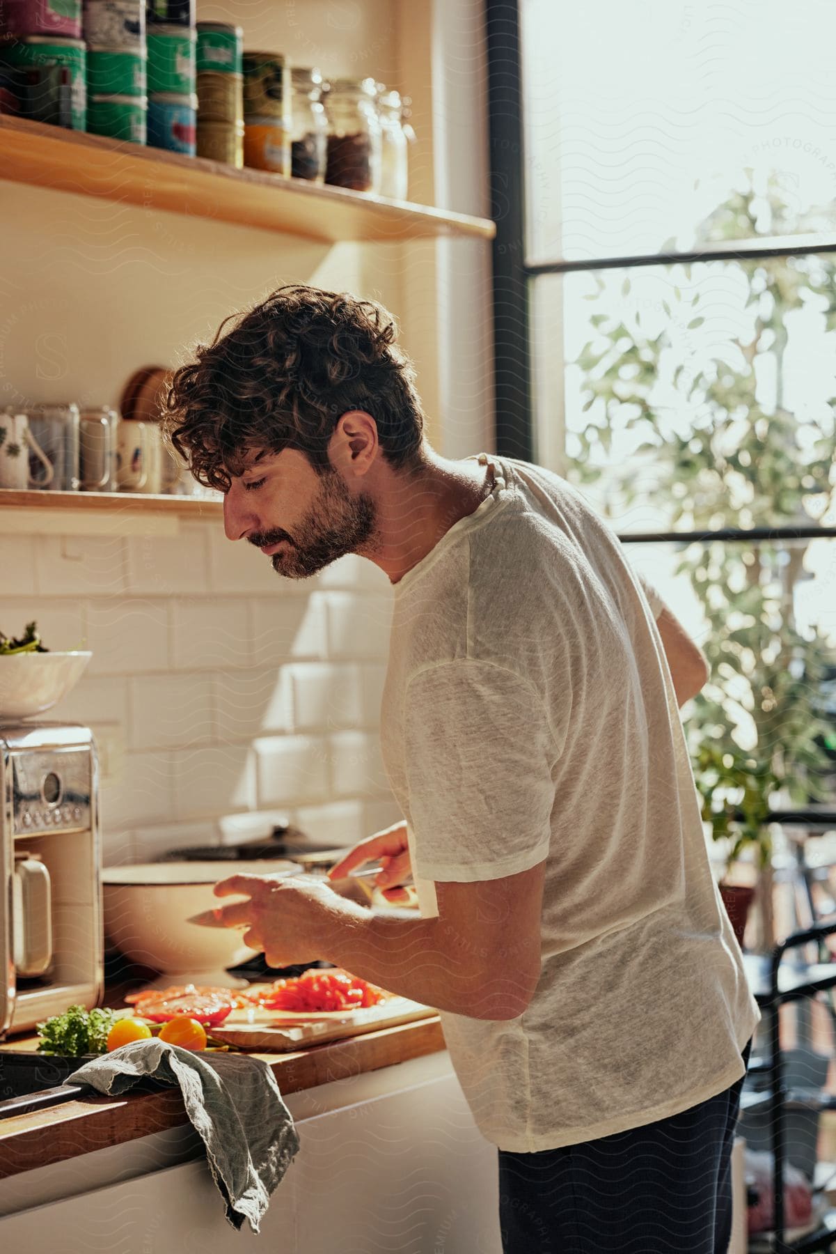 A man is standing at the kitchen counter chopping vegetables