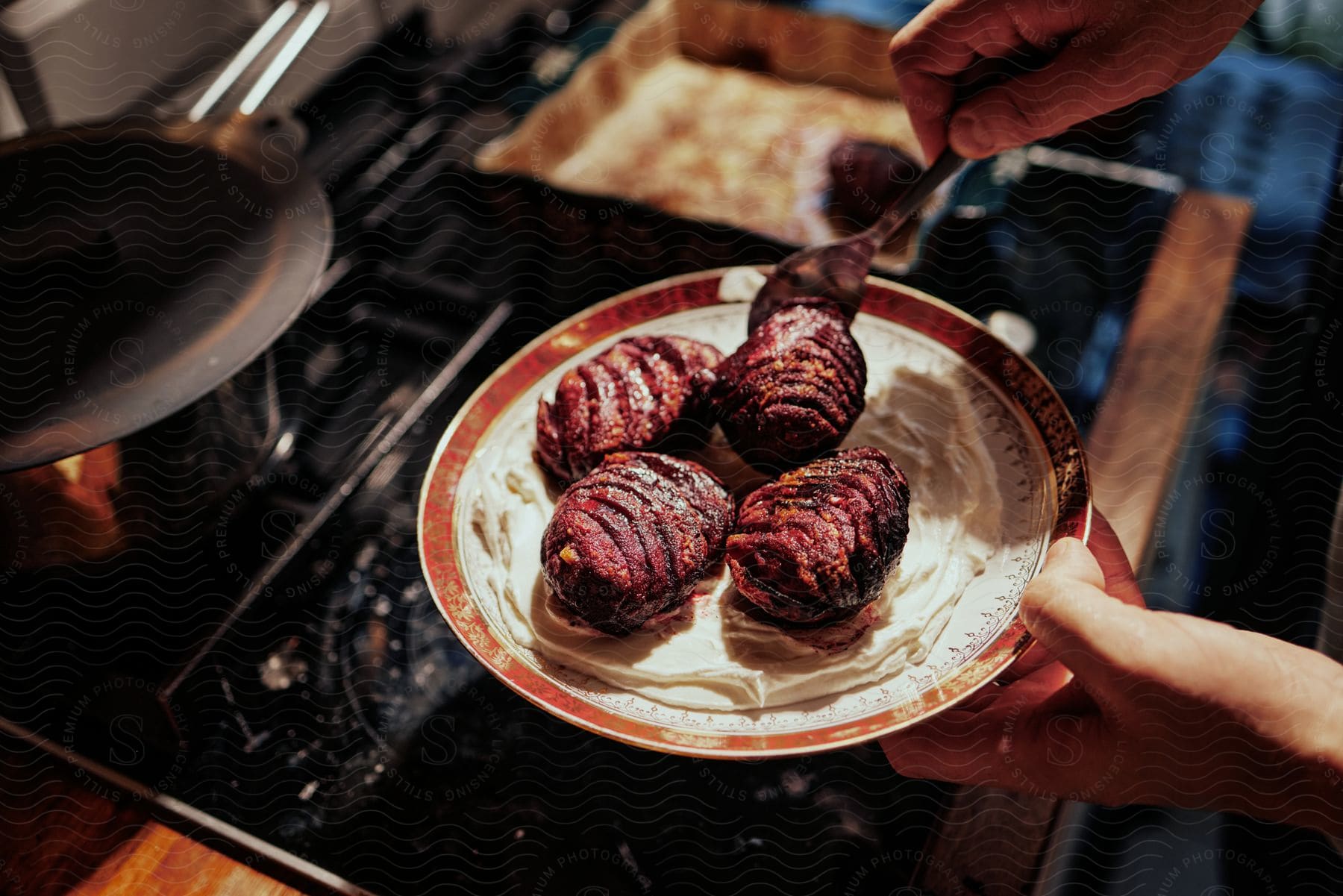 Person holds a plate of steak and mashed potatoes above a stove with a spoon in the meat.