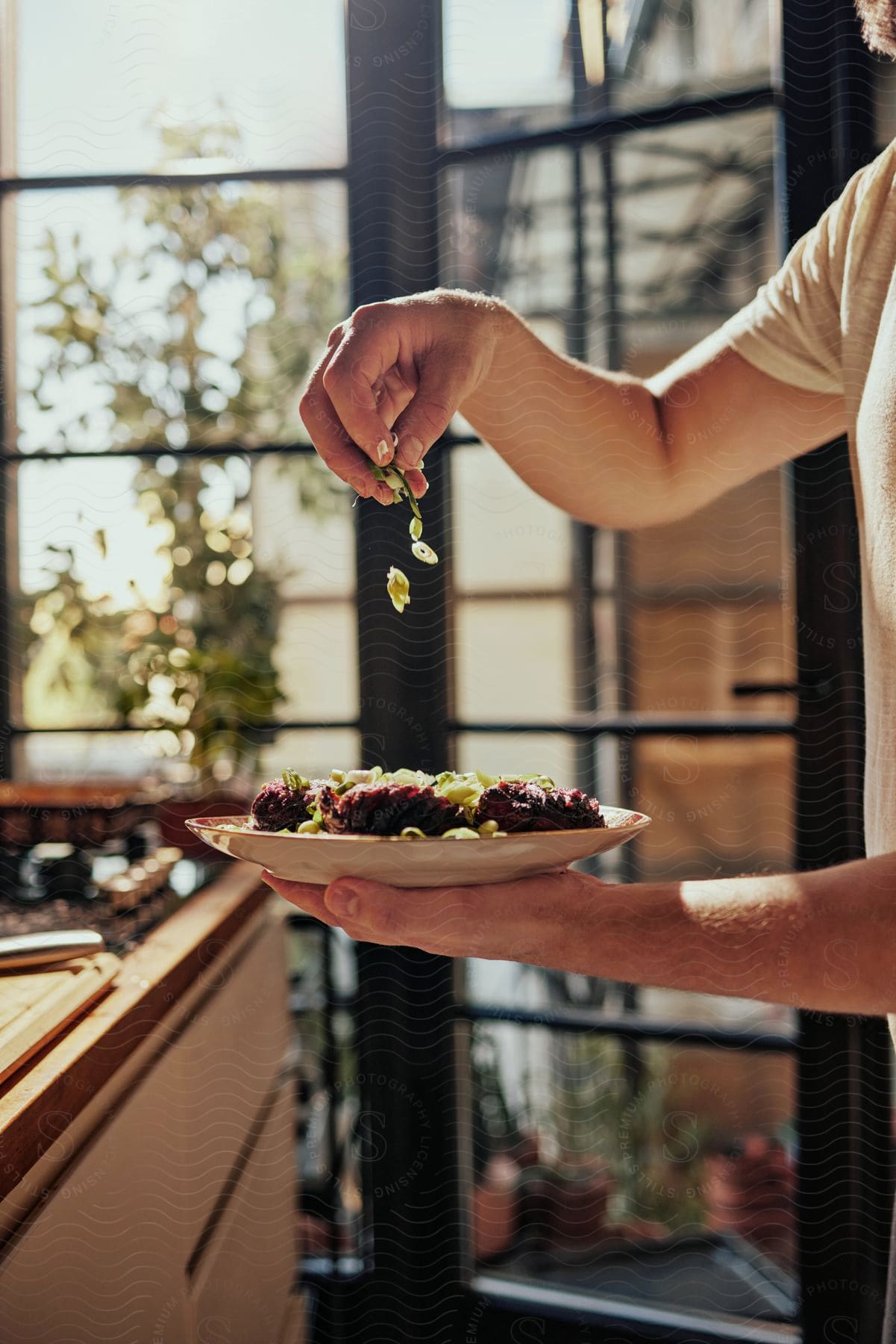 A man is holding a plate and dropping ingredients on to the food