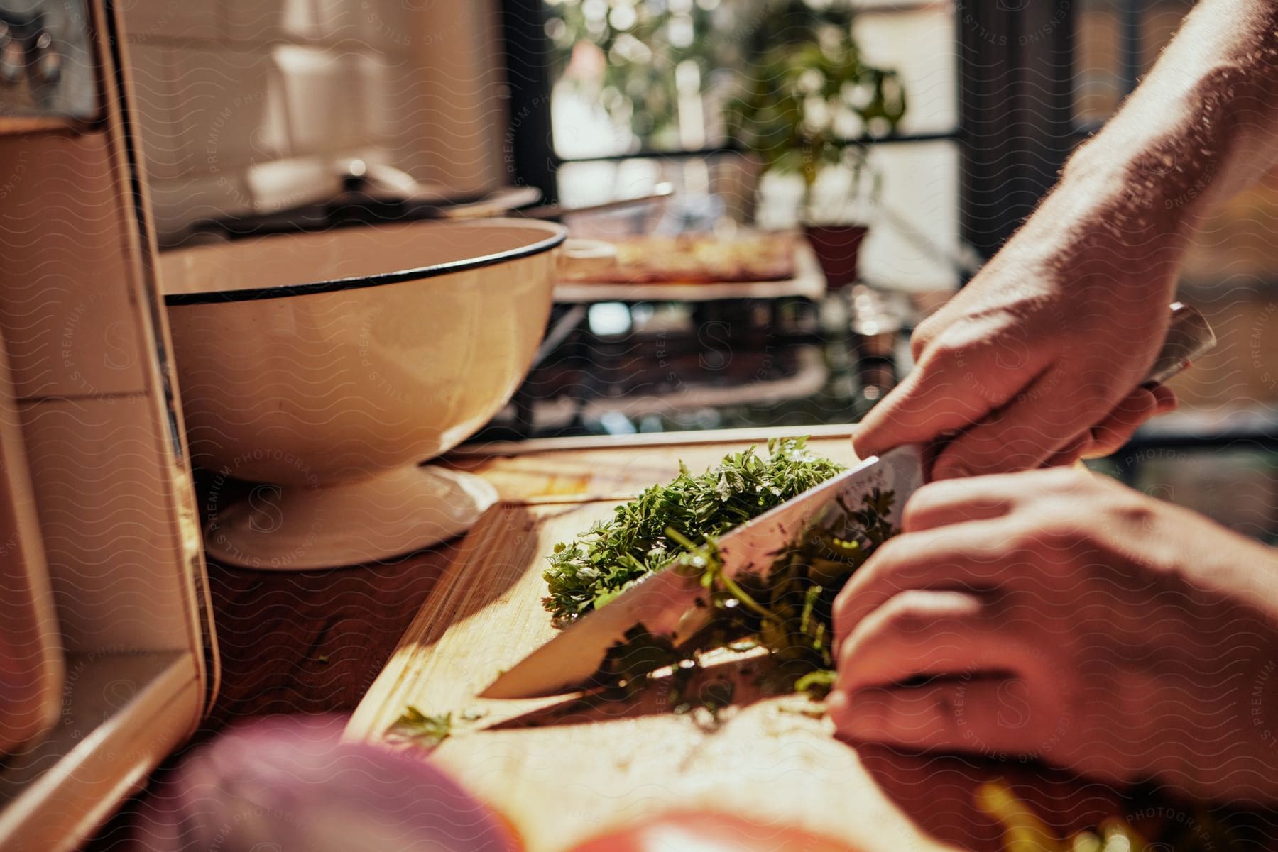 A cook is standing at the kitchen counter chopping herbs