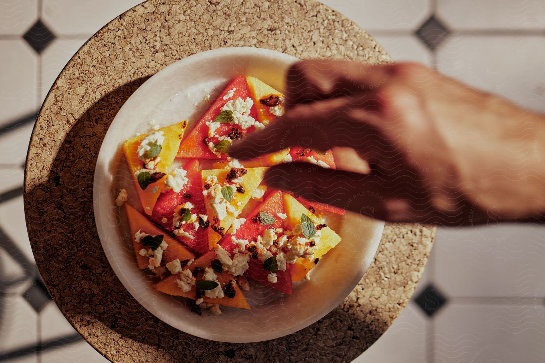 A cook is dropping ingredients onto a plate of food