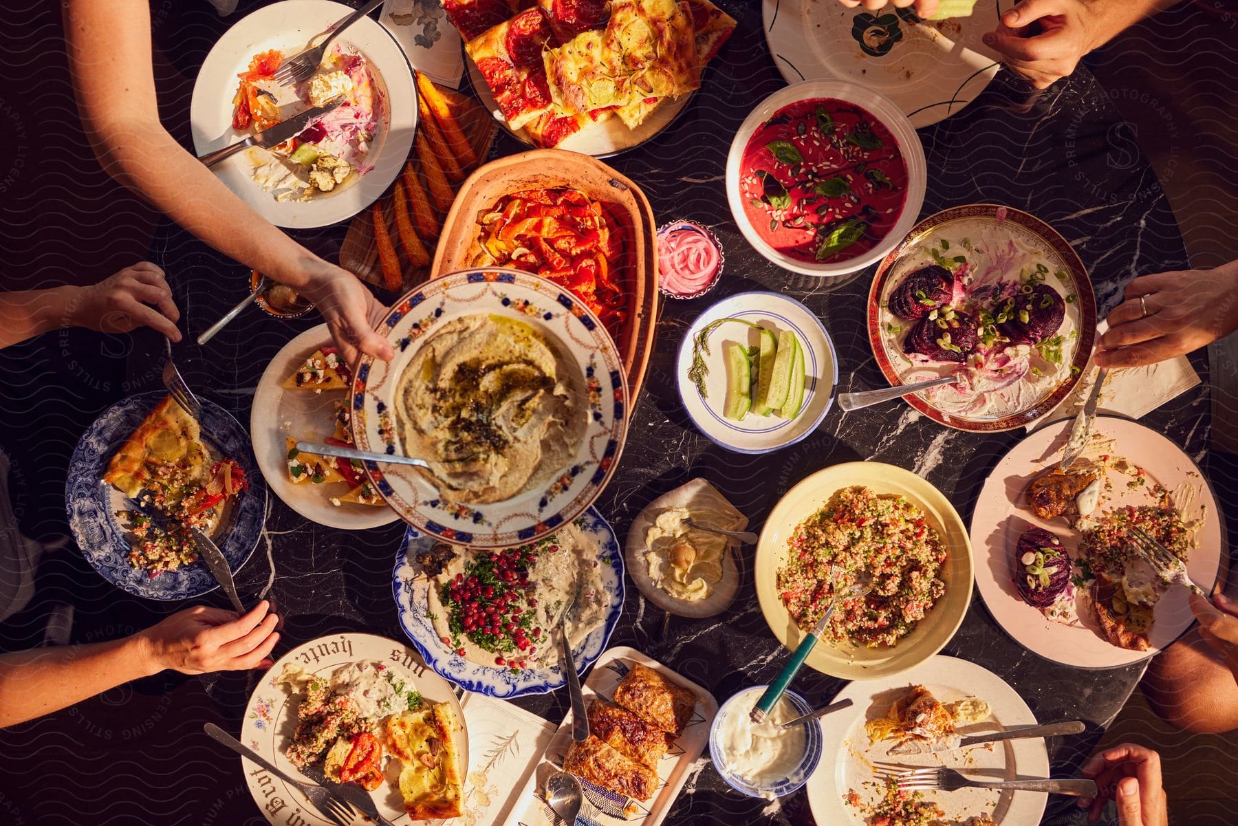 A small group of people are seated around a table sharing many dishes of cooked food.