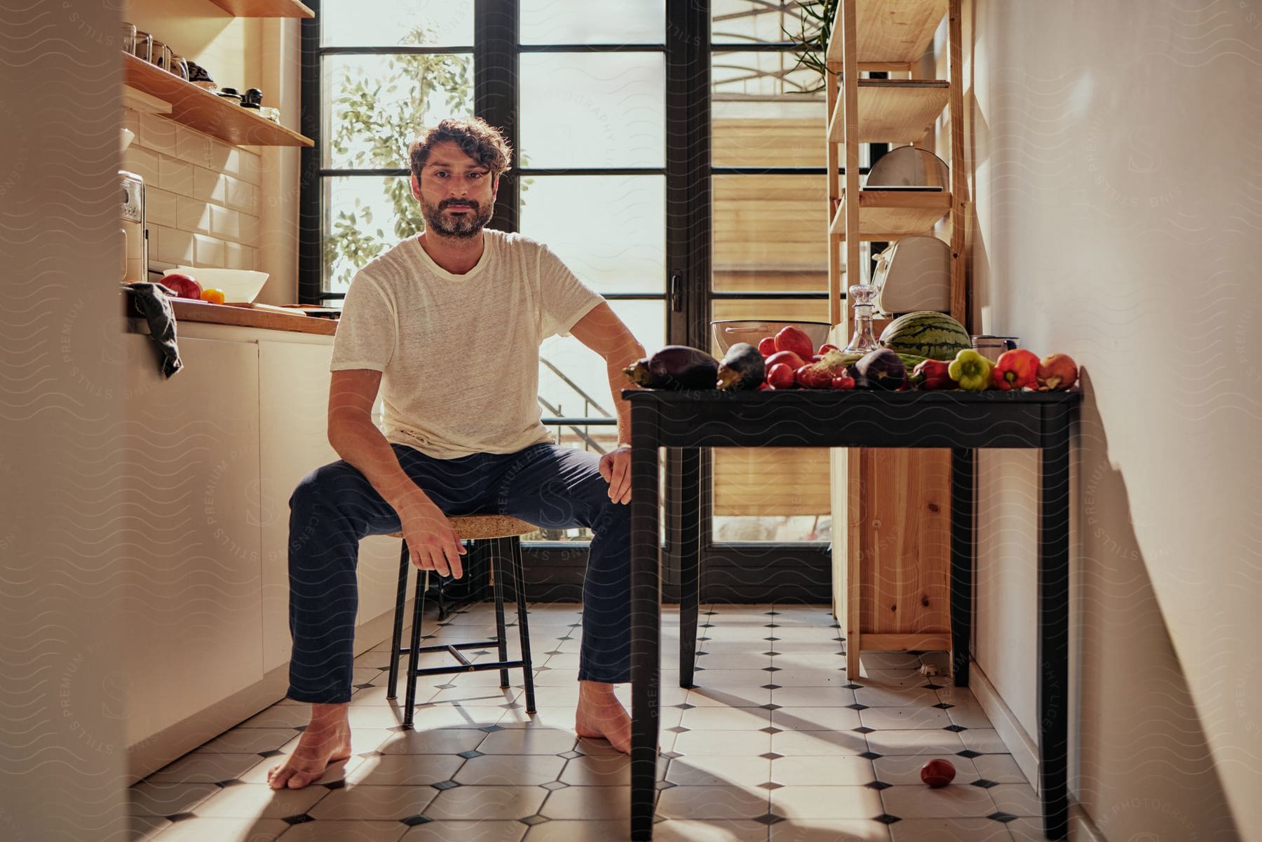 Man Sitting Next To A Table Filled With Vegetables And Fruits