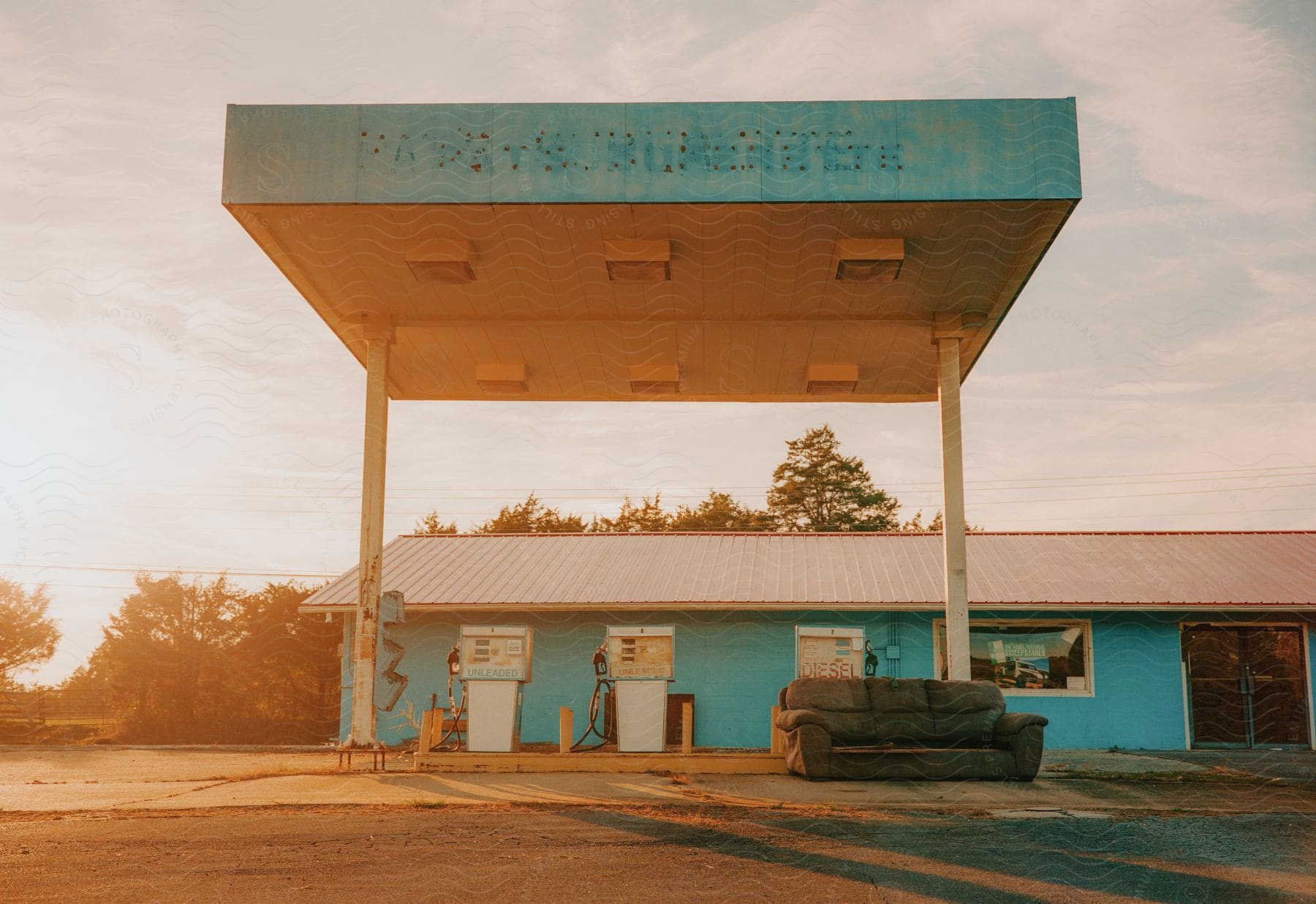 Exterior view of light blue gas station at sunset