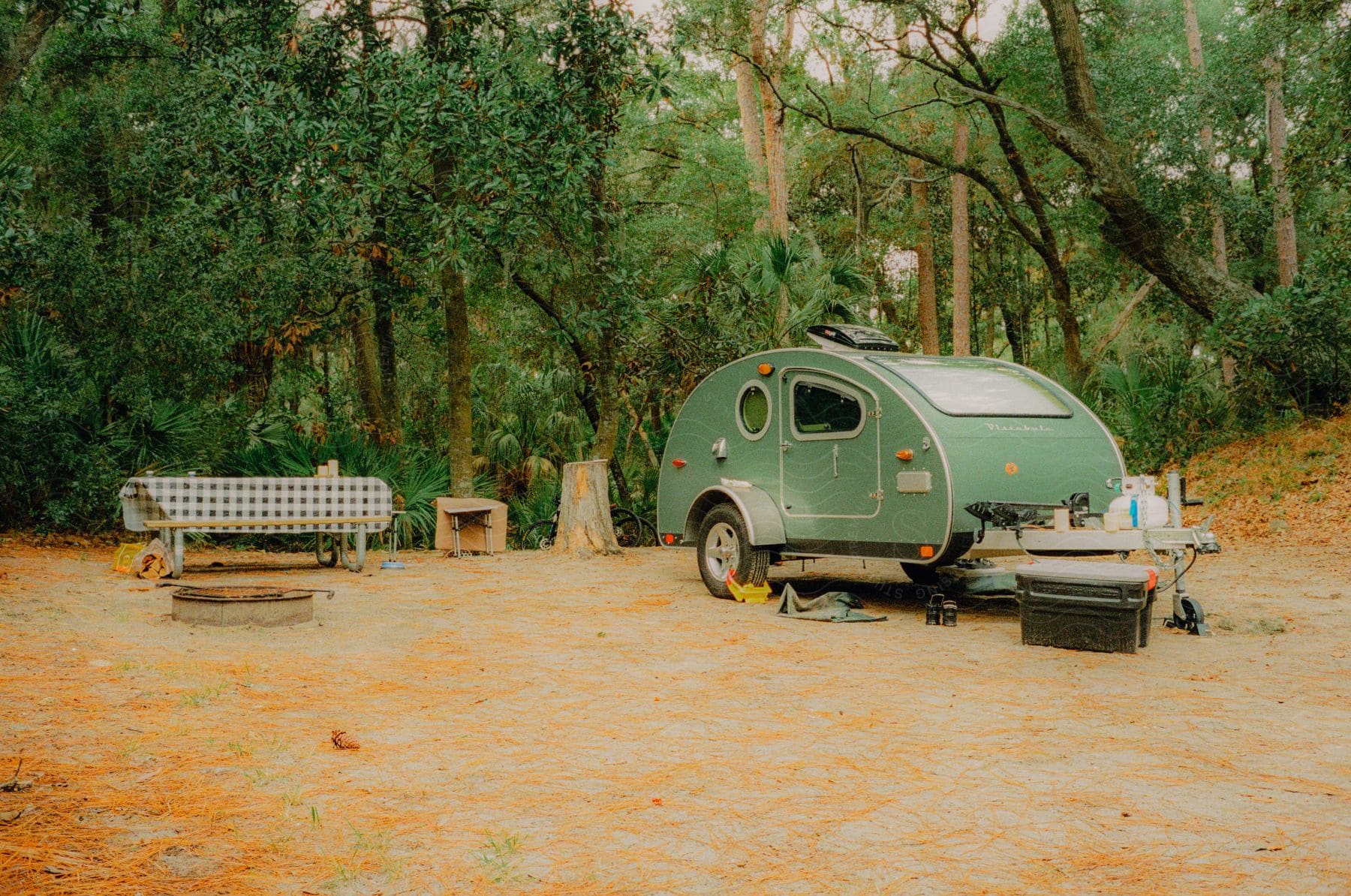 A camping trailer out in the middle of a forested area.