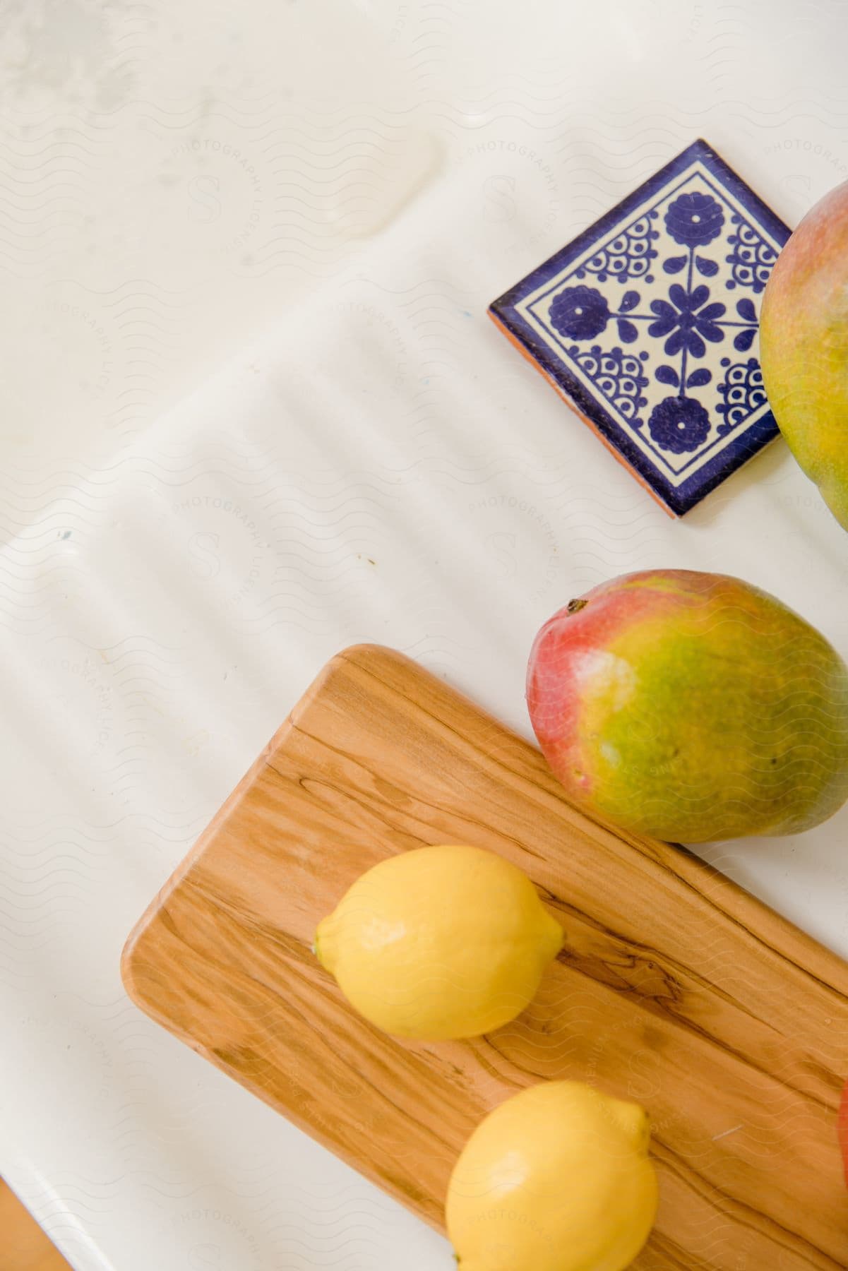 Sicilian lemons and mangoes on a cutting board and ceramic dish.