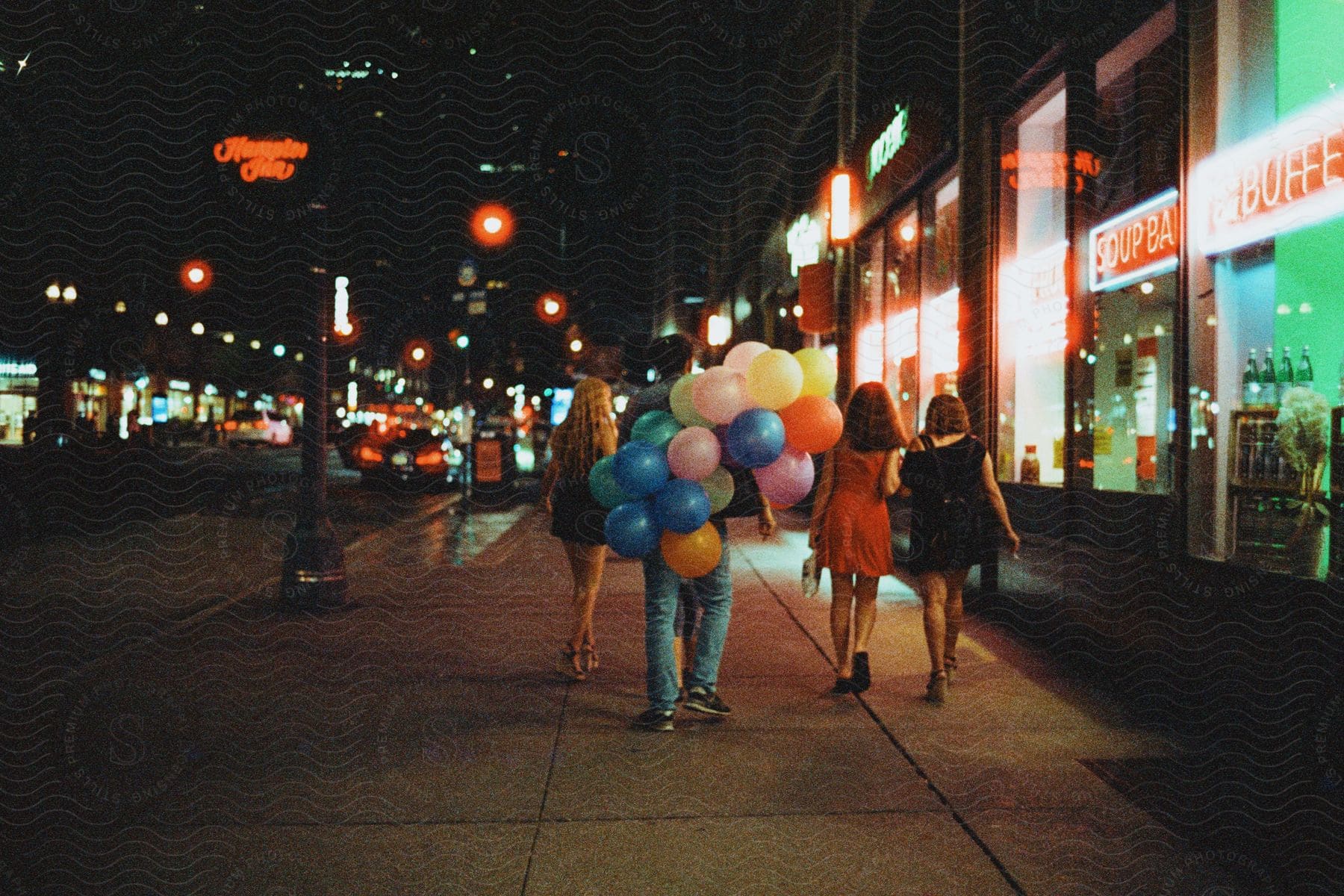 People walking with their backs turned on a sidewalk at night in a metropolis.