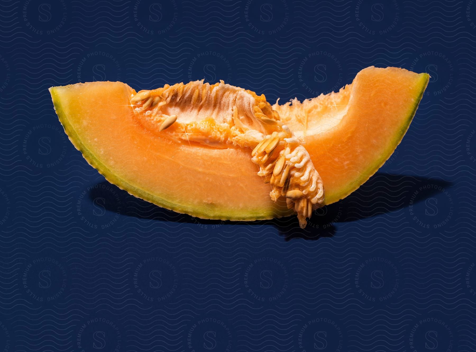 A close-up of a slice of cantaloupe on a blue surface.