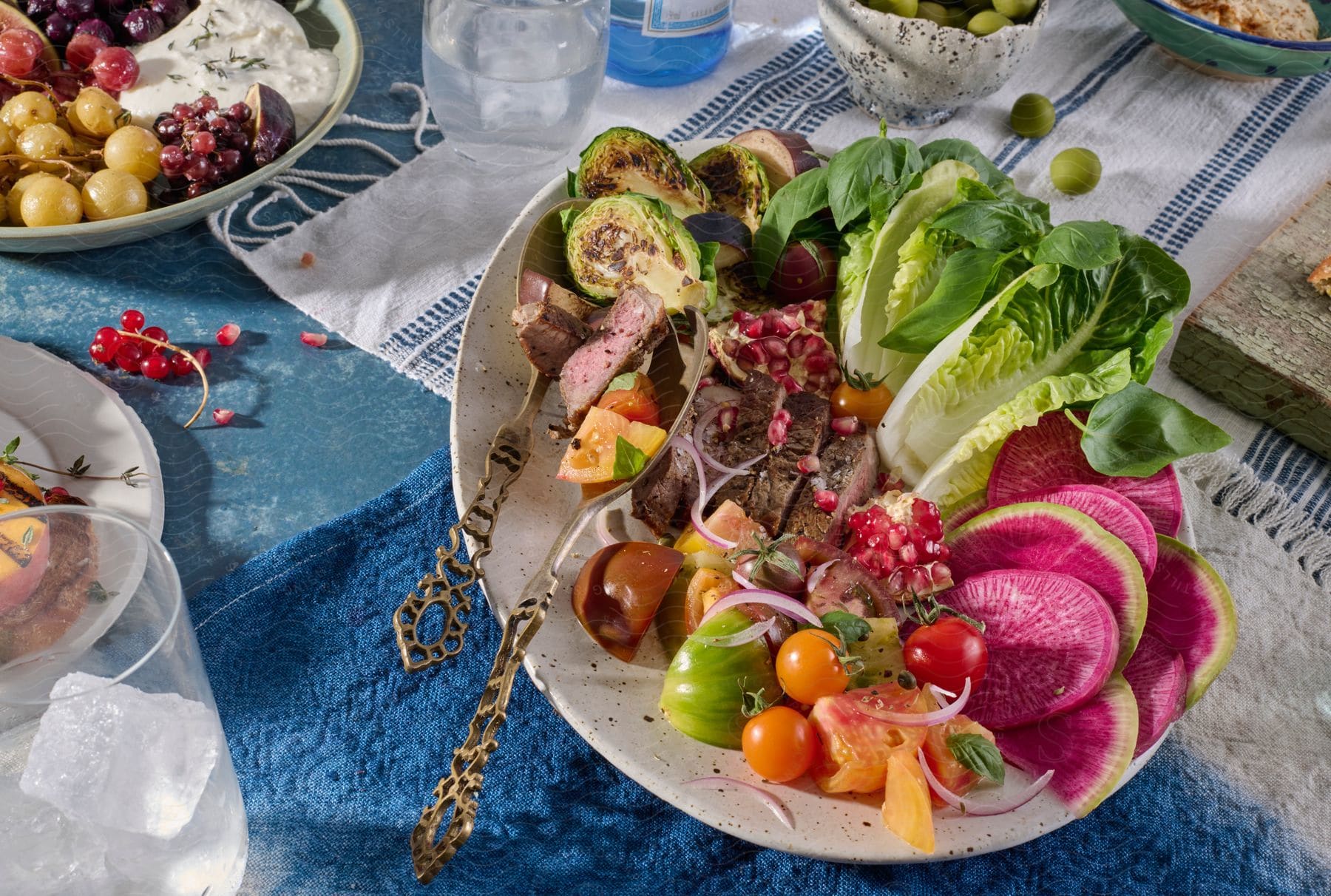 a plate of food including beef, carrots, broccoli, cauliflower, tomatoes, grapes, and strawberries. sitting on top of a table