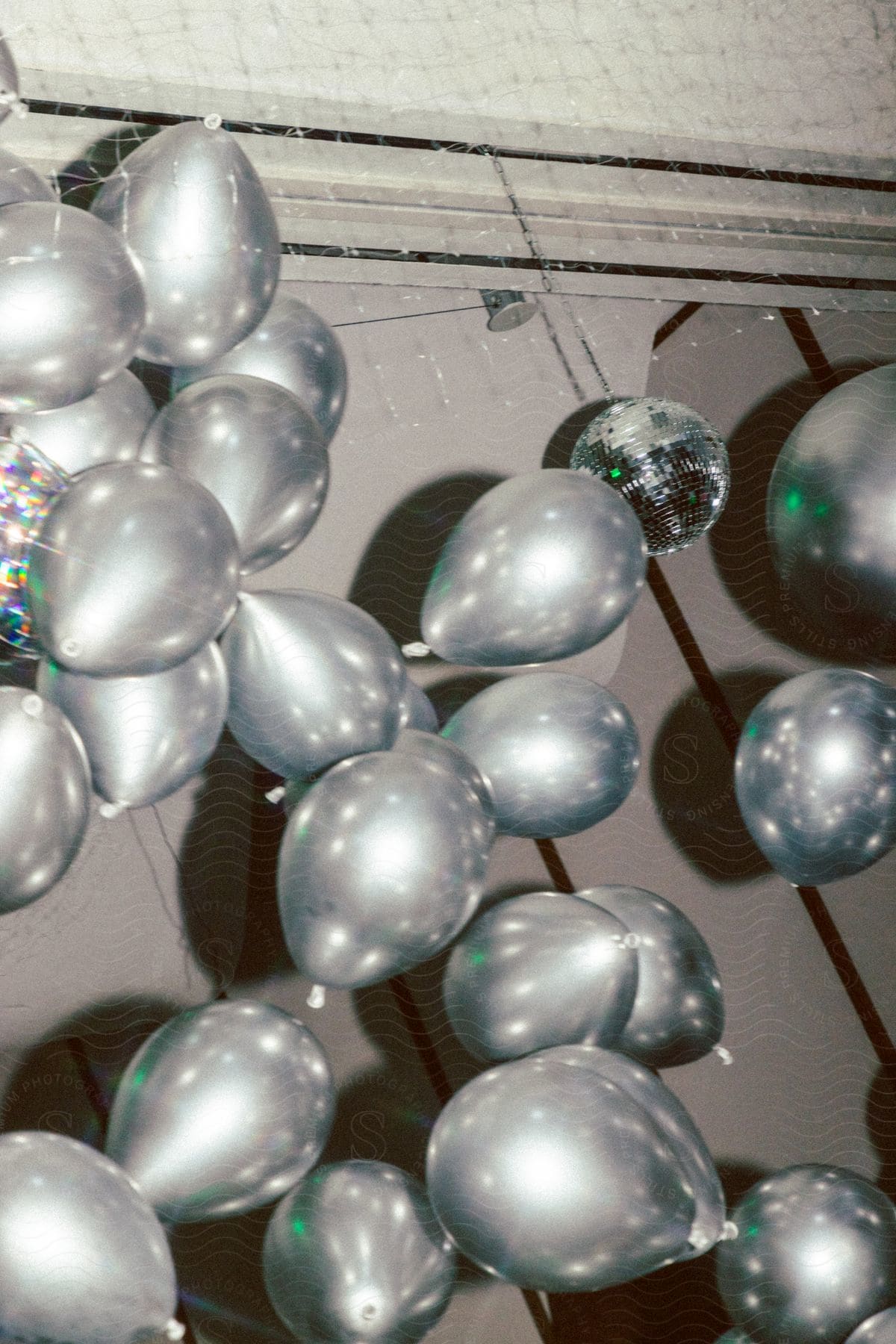 View of silver balloons and a shiny disco ball in an indoor setting.