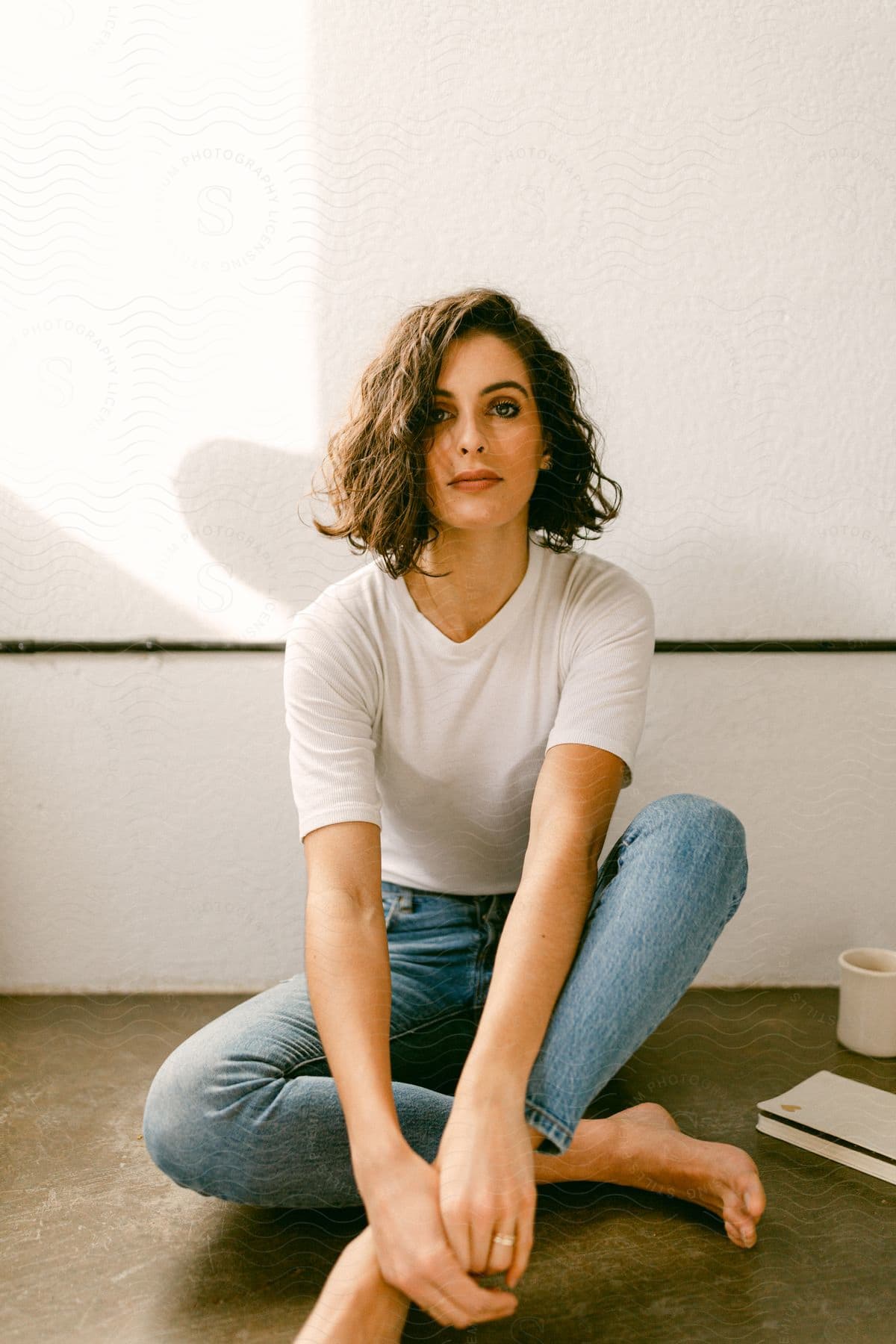 dark haired woman with bob hairstyle, white t-shirt and jeans sits posing