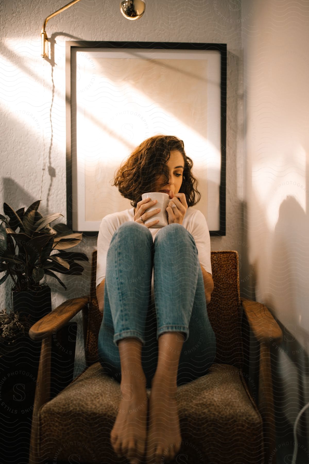 woman with dark hair wearing jeans and tshirt hold coffee mug chin level