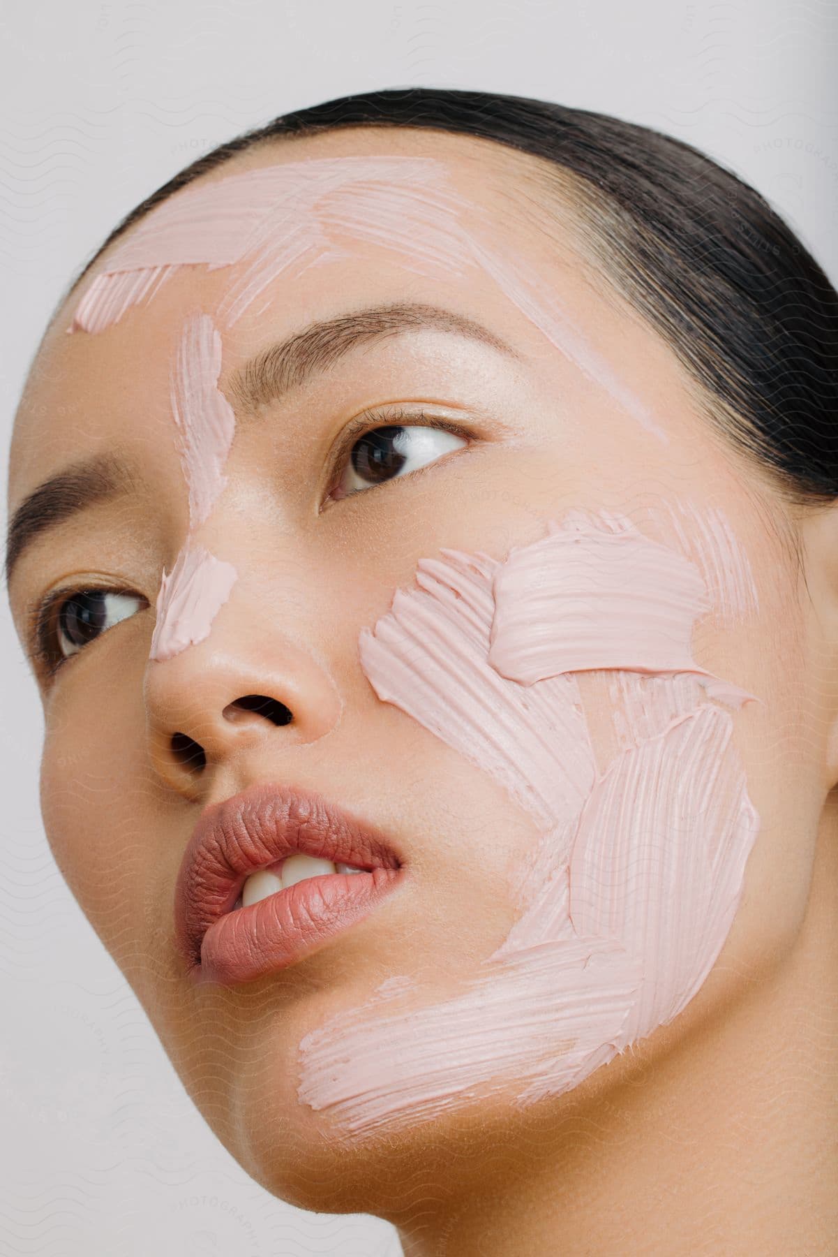 Face of a young Asian woman with creams on her face.