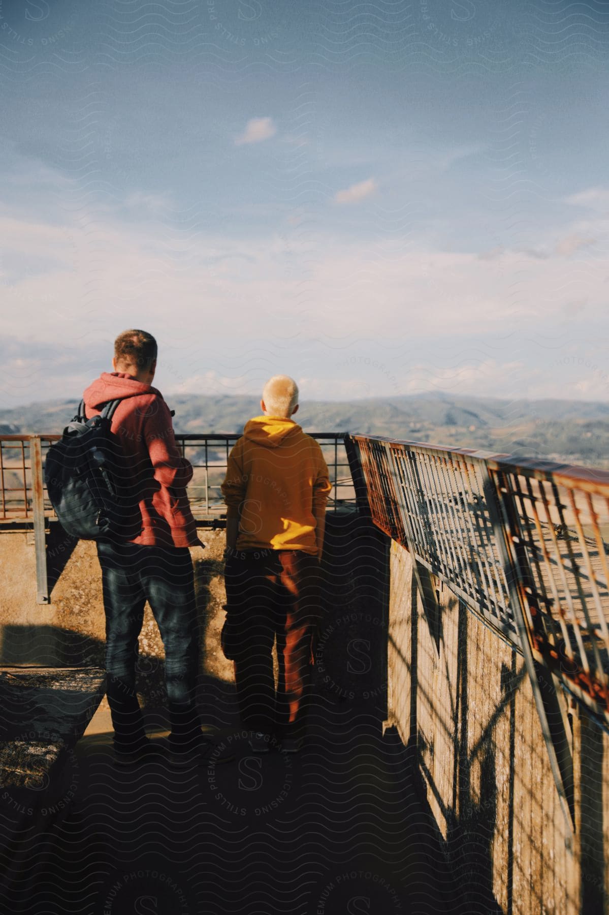 Man and woman standing on viewing platform look at misty landscape.