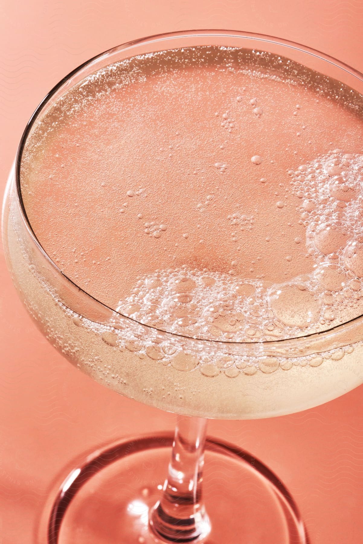 A glass of beverage with bubbles on top.