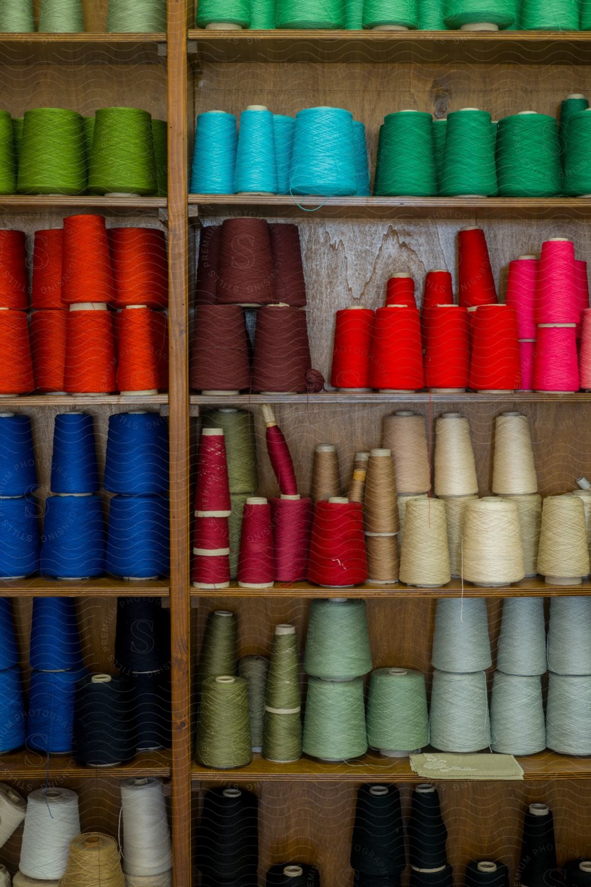 Brown shelves with multiple spools of thread of various colors on them.