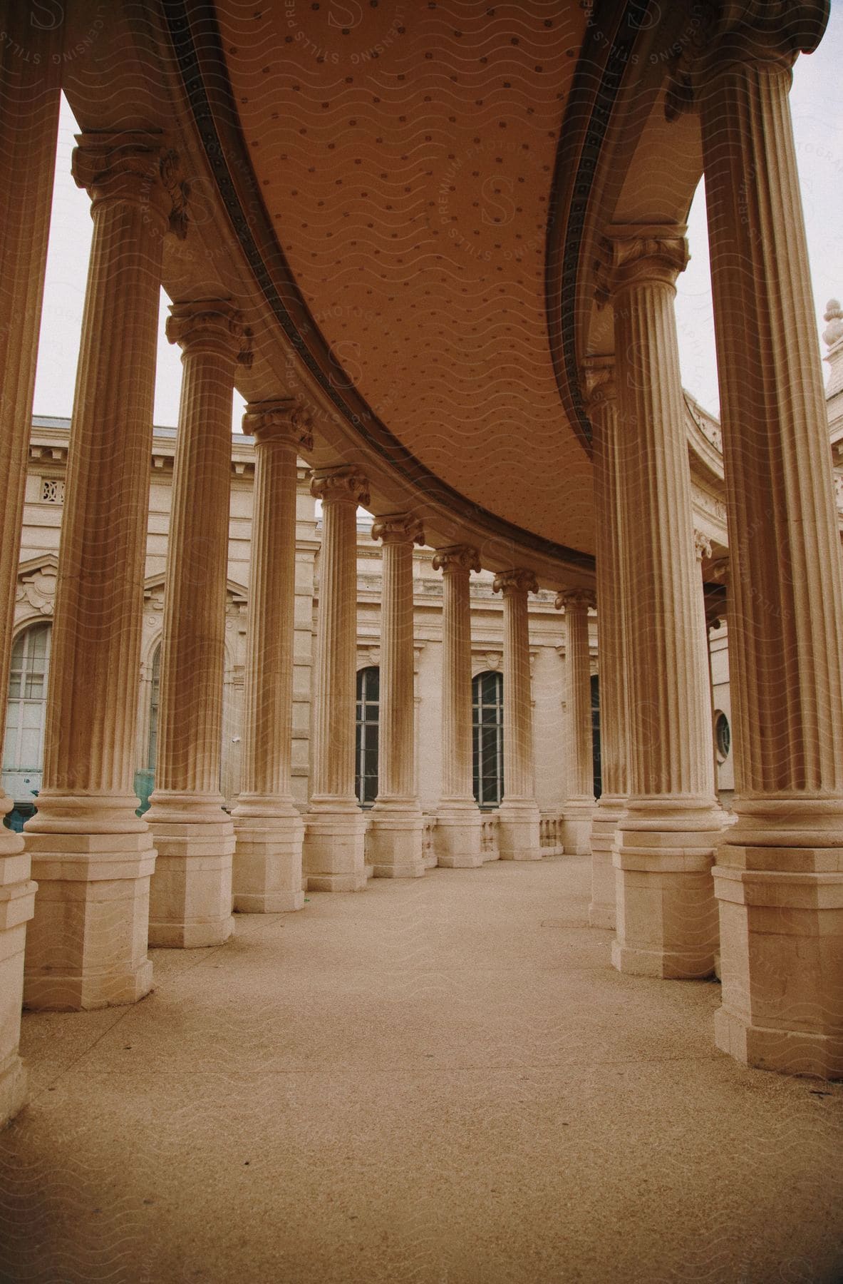 Columns line curving covered path near historic landmark.