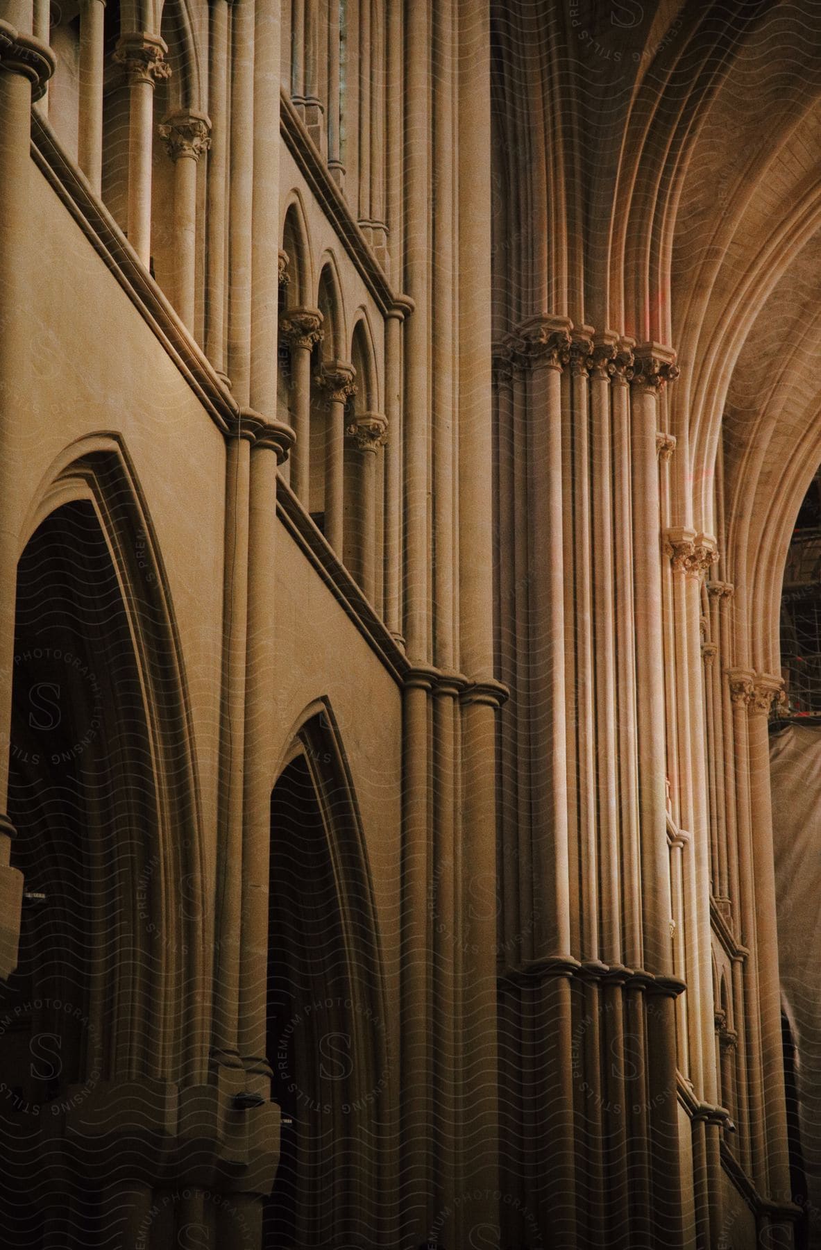 Interior architectural detail of a cathedral showing a series of tall, arched columns and ribbed vaulting.