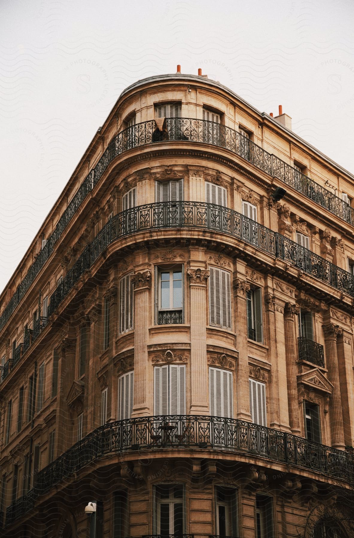 Curved facade of a traditional Parisian apartment building with wrought-iron balconies and tall windows.