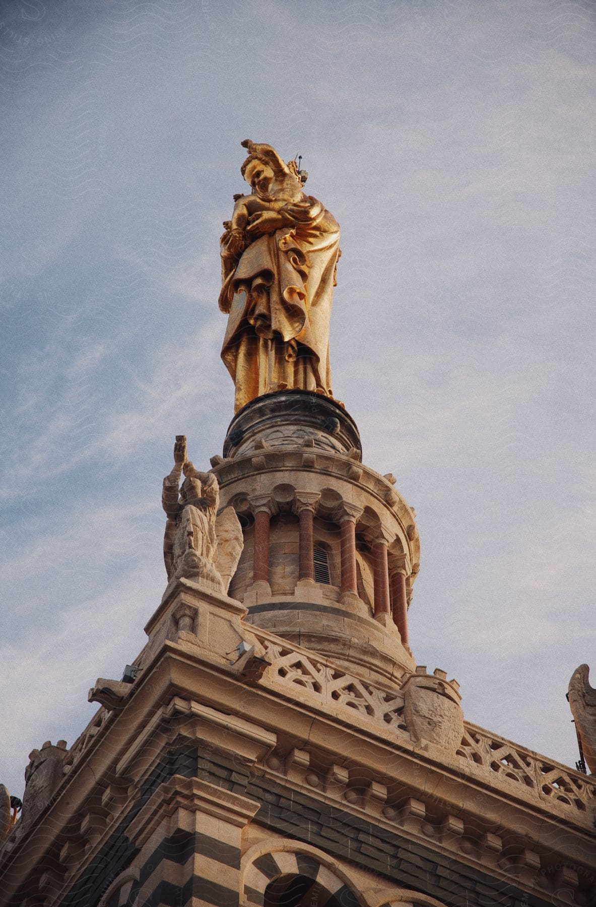 statue at the top of a gold-painted building with symbols