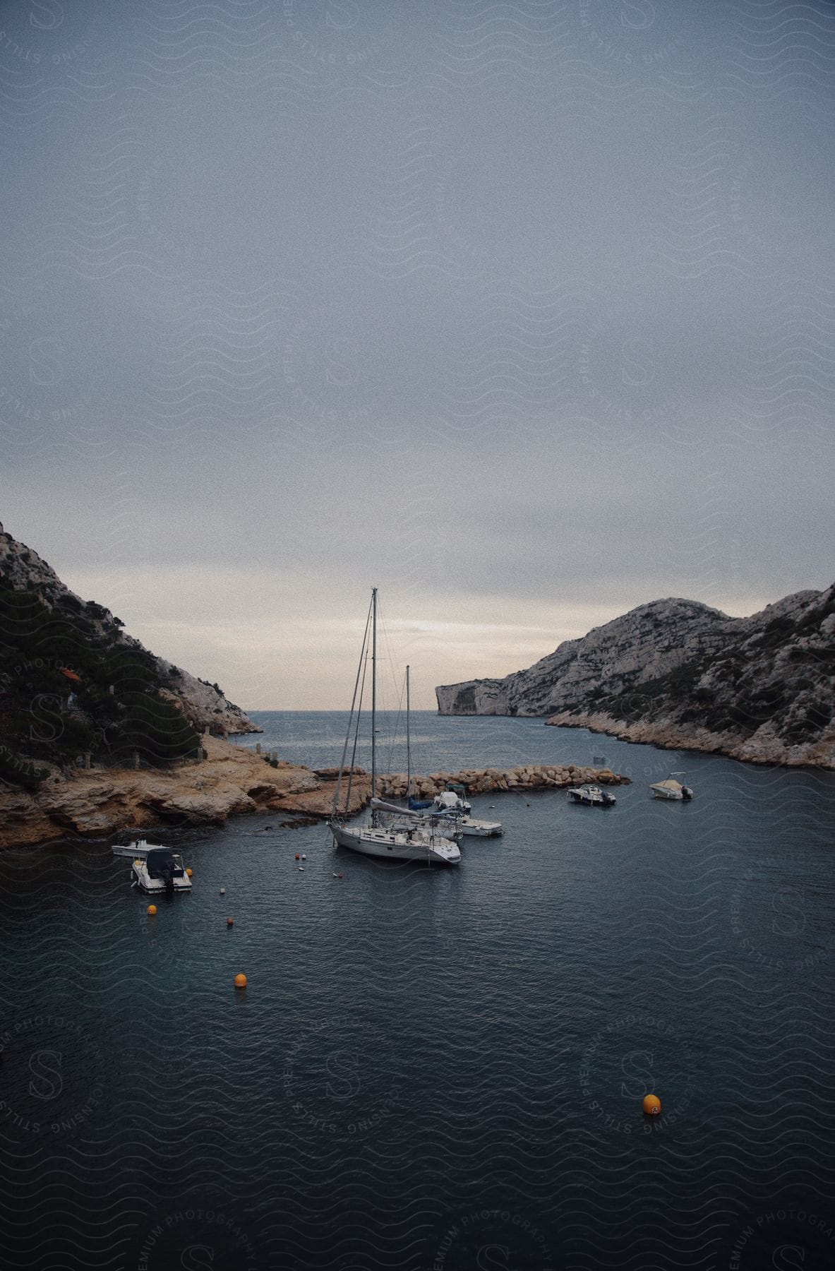 Boats are sailing in a river between mountains off the coast of a landform