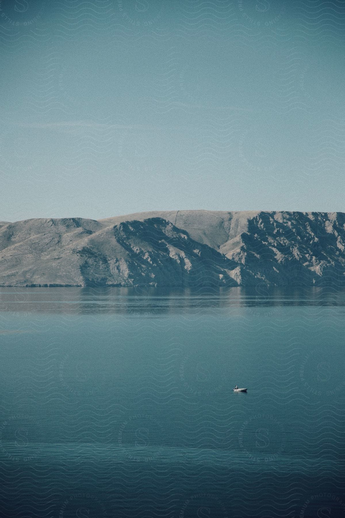 A boat is in the middle of the water near a mountain.