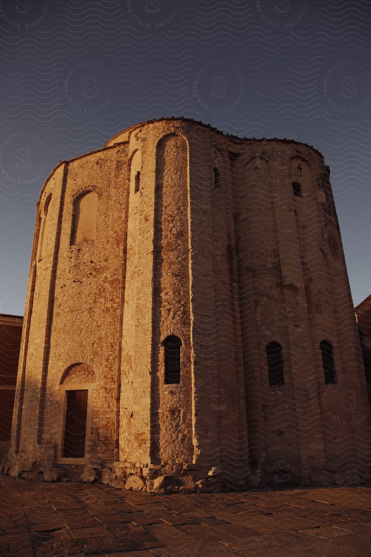 The setting sunlight colors the rounded stone exterior of St Donatus' Church in Croatia