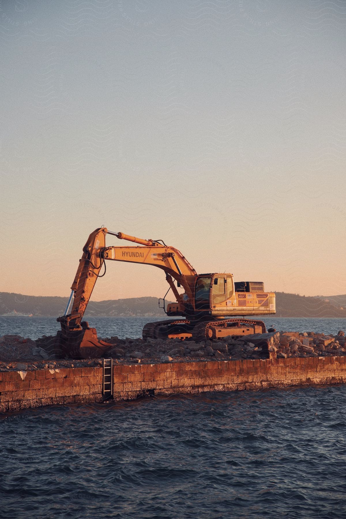 An excavator sitting out on some dirt next to water.