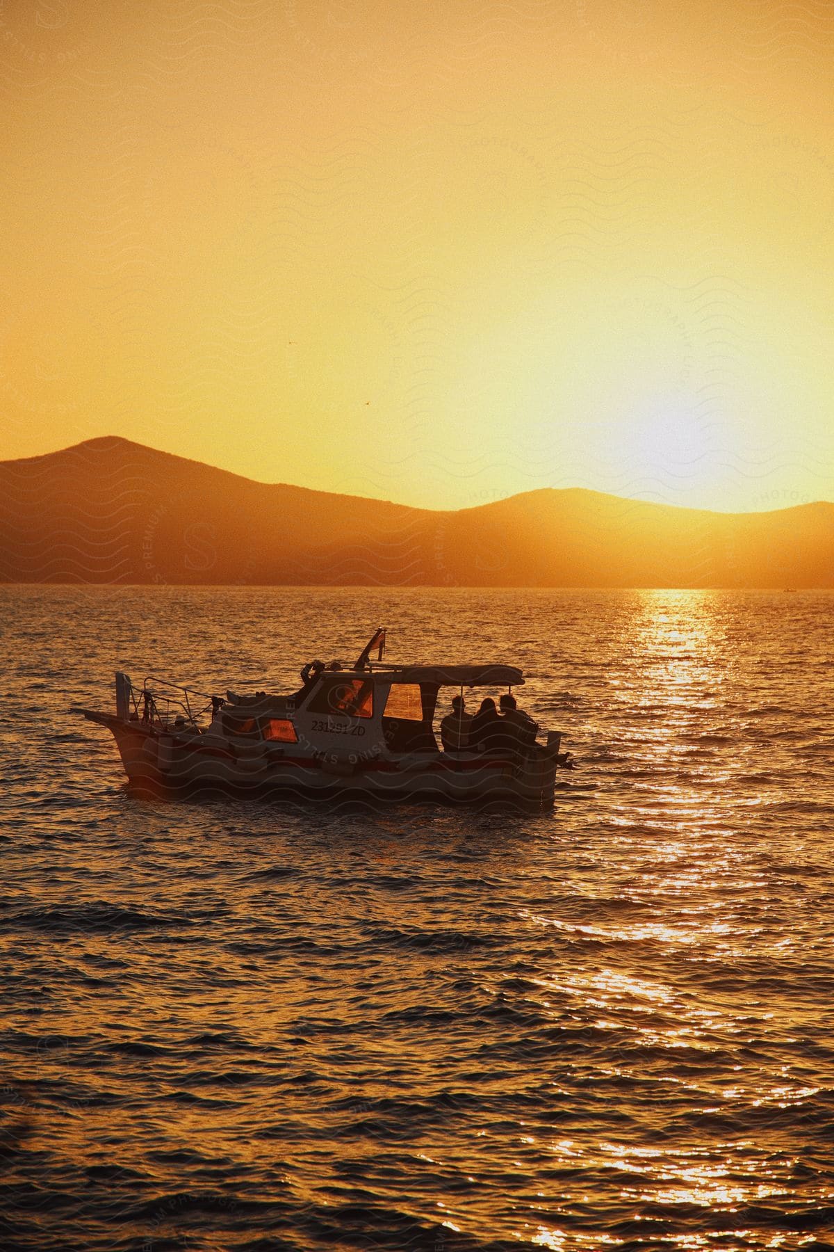 A group of people watches the sunset on a boat as it floats on the water.