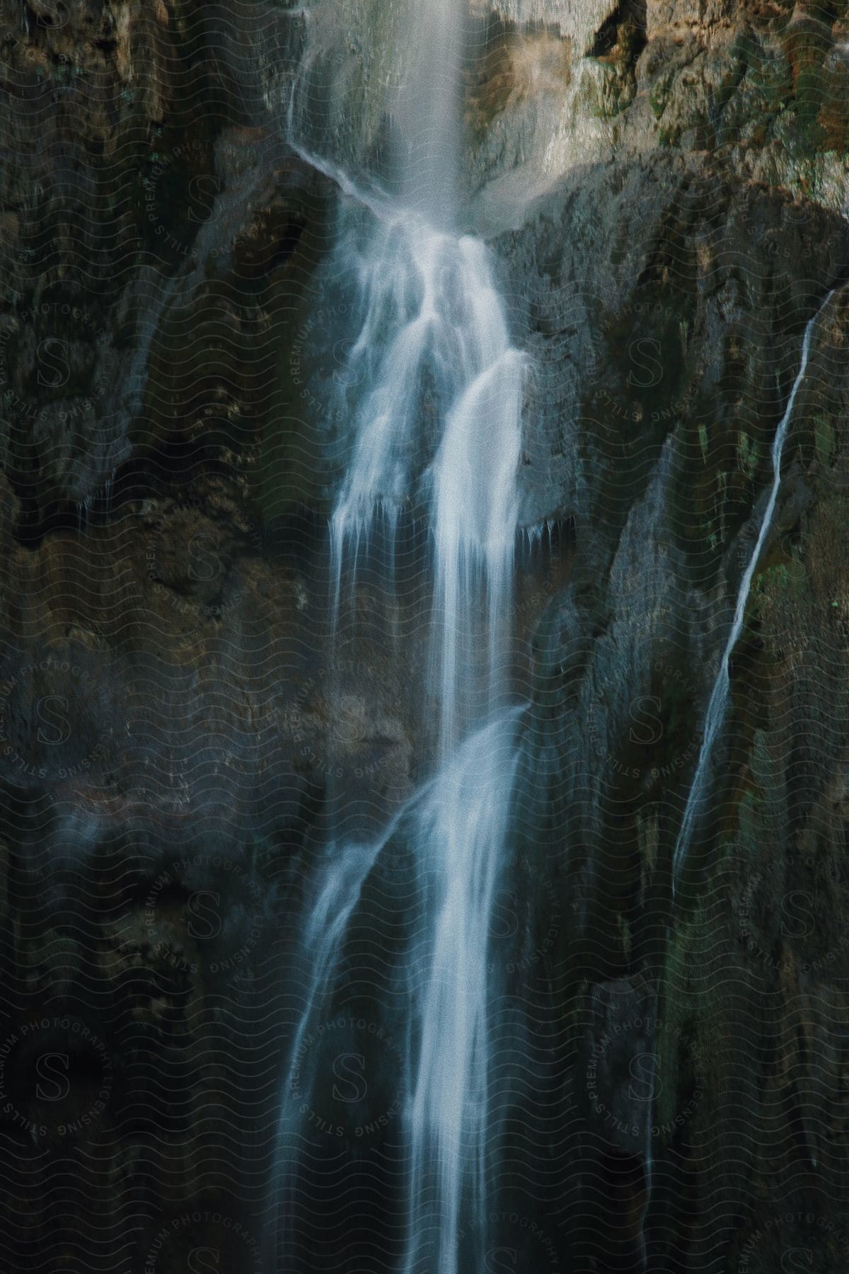 A small waterfall with water falling from a huge rock.