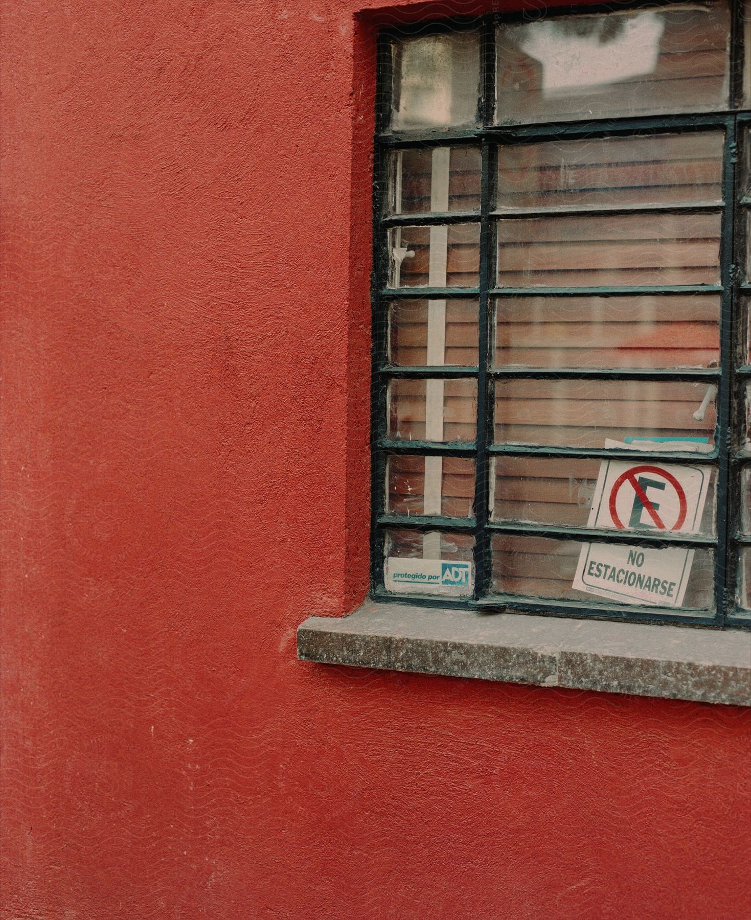 A window and a red wall on the side of a building outdoors.
