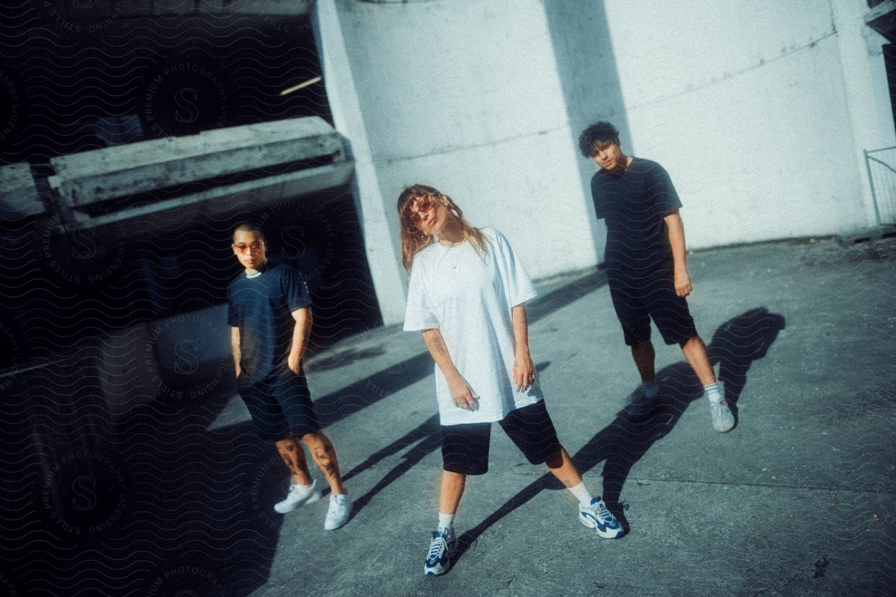 Three young people are standing in formation in an alley