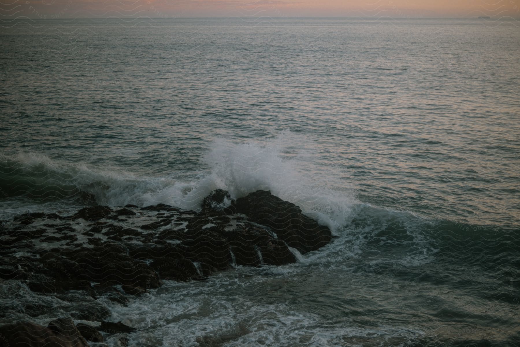 Waves splash against rocks along the coast as they roll into shore