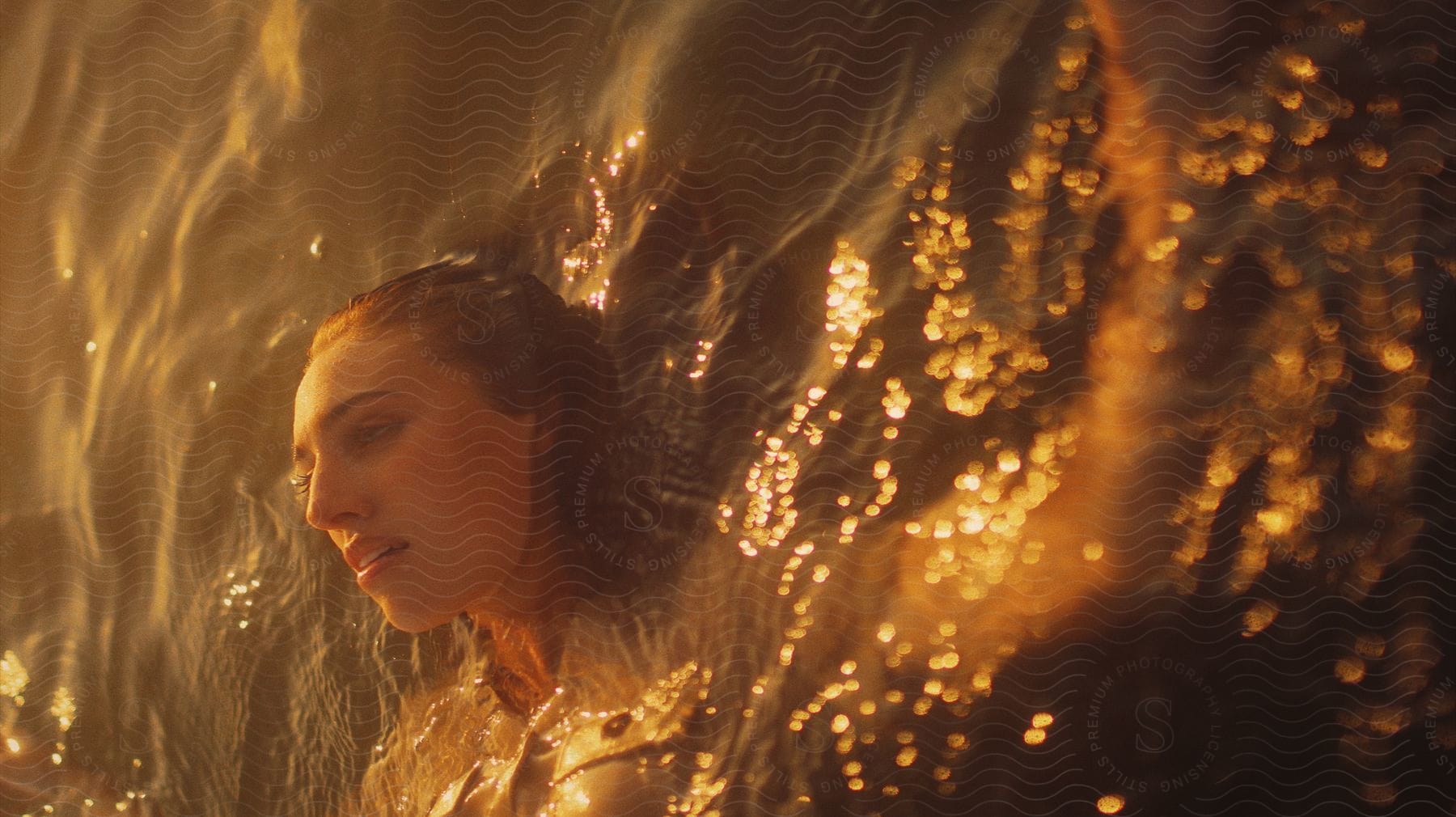 Golden sunlight shines on a woman's face and illuminates the water as she floats on her back